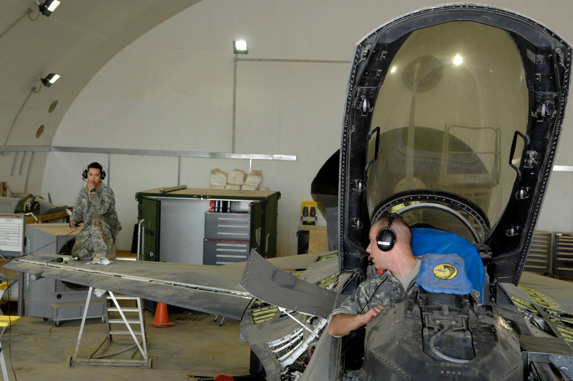 JOINT BASE BALAD, Iraq -- Staff Sgt. Caesar Rivera and Airman 1st Class Shane Bridges, 332nd Expeditionary Aircraft Maintenance Squadron crew chiefs, communicate back and forth during a test of the leading edge flap as part of a phase inspection on an F-16 Fighting Falcon here, June 18. The flap is responsible for providing additional lift and drag that is critical for movement at slower air speeds. A phase inspection checks critical aircraft systems to ensure they are in working order and can continue to fly combat missions over Iraq. Sergeant Rivera is deployed from Nellis Air Force Base, Nev., and Airman Bridges is deployed from Shaw Air Force Base, S.C. (U.S. Air Force photo/ Senior Airman Julianne Showalter)