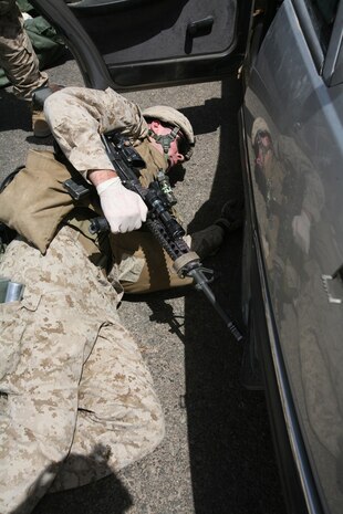 Lance Cpl. Sean W. Ward, 23, a team leader with Company I, 3rd Battalion, 4th Marine Regiment, Regimental Combat Team 5, searches the undercarriage of a vehicle in Hit, Iraq, June 21. Marines conducted an intelligence raid to capture a known insurgent in the Hit area. However, at the end of the operation, Marines had detained a total of four insurgents.::r::::n::