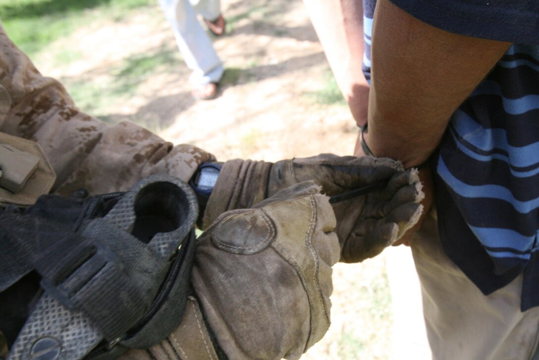 Lance Cpl. Edwin S. Contreras, 19, an assaultman with Company I, 3rd Battalion, 4th Marine Regiment, Regimental Combat Team 5, flexi-cuffs a known insurgent in Hit, Iraq, June 21. Marines with Company I detained four known insurgents during an intelligence raid in the Hit area. The Marines were ecstatic with how the raid turned out. They were in search of one insurgent, but were able to capture three additional insurgents by the end of the day.::r::::n::
