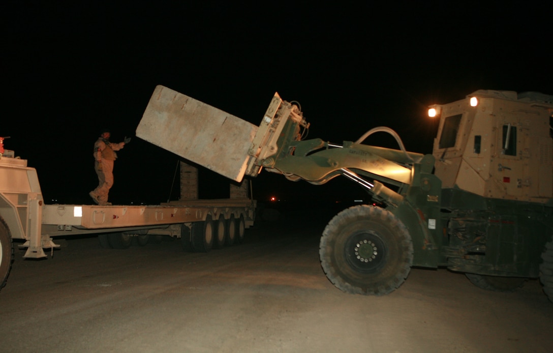 William G. Wilson, from Kyle, Texas, who is a heavy truck driver works with a Marine from Motor Transport Company, Combat Logistics Battalion 1, 1st Marine Logistics Group, to remove concrete barriers from a road near Fallujah, Iraq, June 21. The Marines and civilian contractors also resupplied Marines at Joint Security Station Cross with concrete reinforcements removed during the demilitarization.