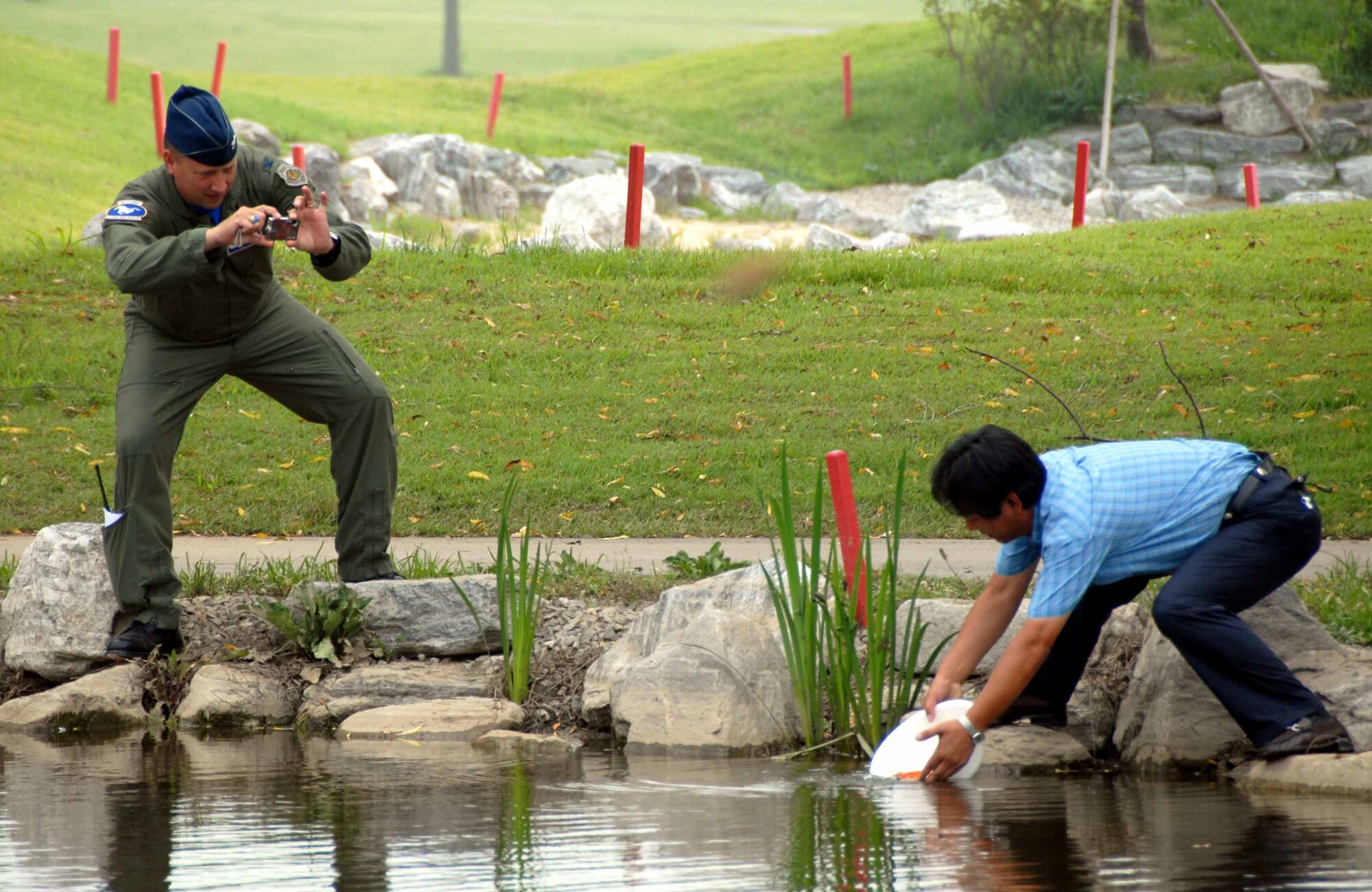 OSAN AIR BASE, Republic of Korea -- Col. Jon Norman, 51st Fighter Wing commander, snaps a photo as a community member releases fish into the Lakes at Osan Golf Course pond June 20. The fish were donated by honorary commander K.D. Lee. (U.S. Air Force photo/Master Sgt. Marlin Zimmerman)