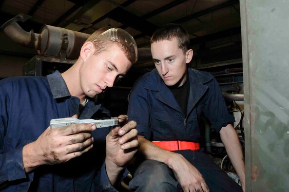 SOUTHWEST ASIA -- Senior Airman Anthony Dodge function checks a zip tie cutter while Airman 1st Class Lucas Lemoine prepares to use it to secure chaffe wrap on hydraulic test stand hoses at a Southwest Asia air base June 18.  Due to the intense heat and mechanical vibrations on the hydraulic test stand wrapping has to be secured to prevent it from coming off.  Both are assigned to 379th Expeditionary Maintenance Squadron. Airman Dodge is deployed from MacDill Air Force Base, Fla. and Airman Lemoine is deployed from Offutt Air Force Base, Neb.  (U.S. Air Force photo/Tech. Sgt. Johnny Saldivar)