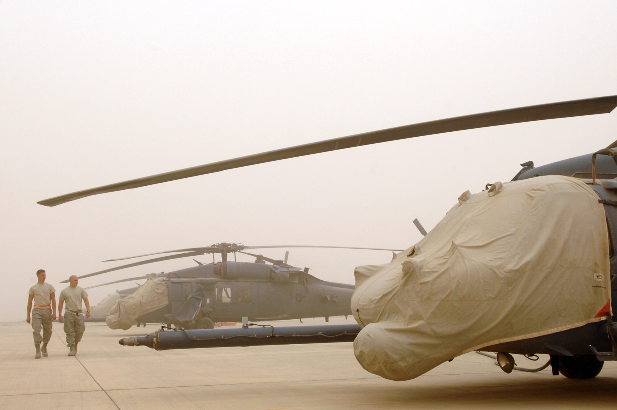 Airman 1st Class Jason Schwenn and Senior Airman Caleb Castillo walk through a row of HH-60G Pavehawk helicopters during a major dust storm April 17 at Joint Base Balad, Iraq. During extreme weather conditions, extra precautions are taken to protect aircraft from weather elements. Both Airmen are 64th Expeditionary Helicopter Maintenance Unit crew chiefs deployed from Moody Air Force Base, Ga. (U.S. Air Force photo/Senior Airman Julianne Showalter) 
