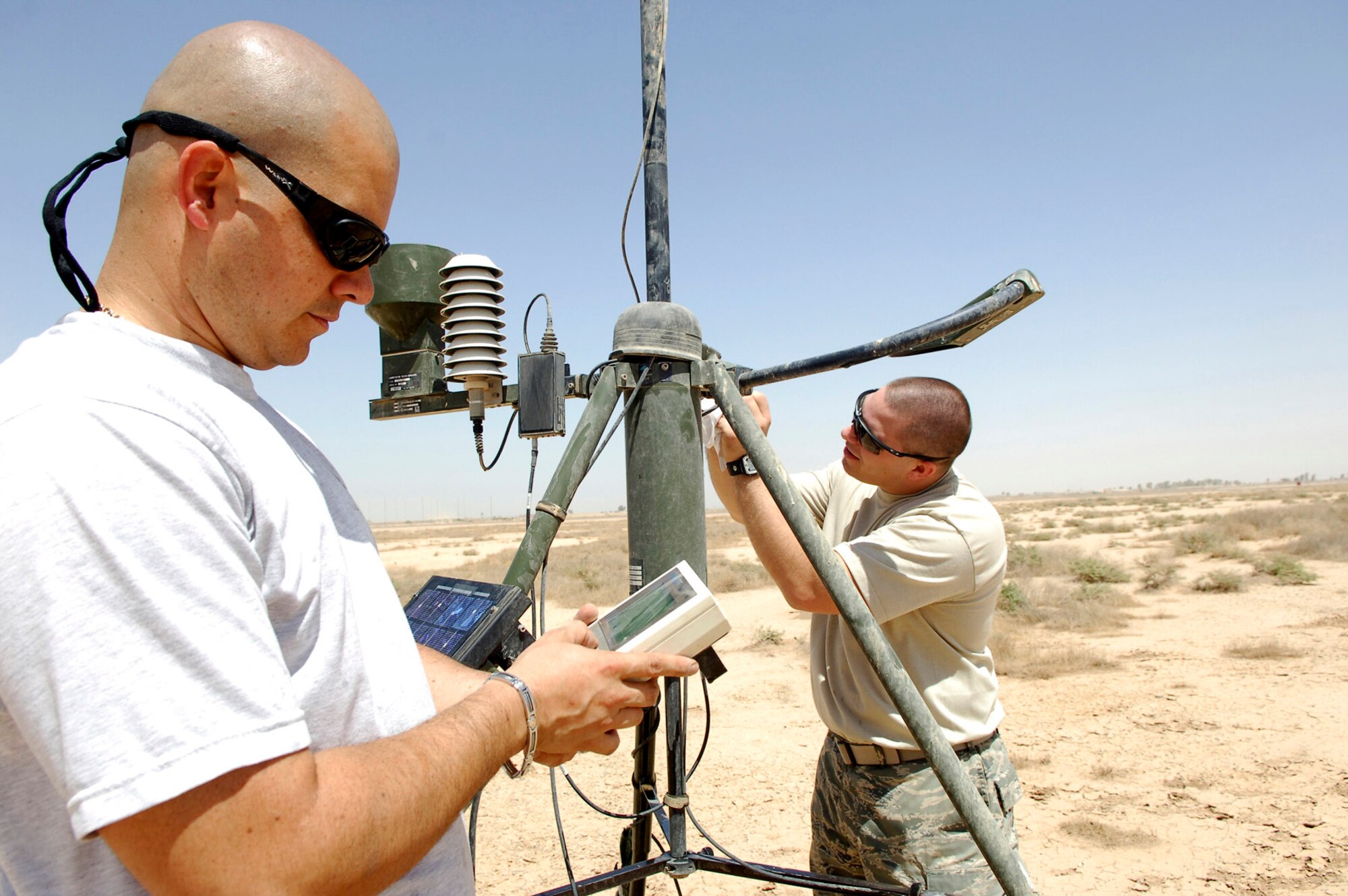 Staff Sgts. Donald Blasini and Richard Skelly work together to ensure the tactical weather equipment is working properly June 14 at Joint Base Balad, Iraq. The equipment, which is positioned on the airfield, monitors weather conditions. Dirty sensors can affect the accuracy of the readings so the equipment must be cleaned regularly. Sergeant Blasini is deployed from Shaw Air Force Base, S.C., and Sergeant Skelly is deployed from Andrews AFB, Md. Both are combat weather forecasters assigned to the 332nd Expeditionary Operations Support Squadron Combat Weather Flight. (U.S. Air Force photo/Staff Sgt. Mareshah Haynes) 
