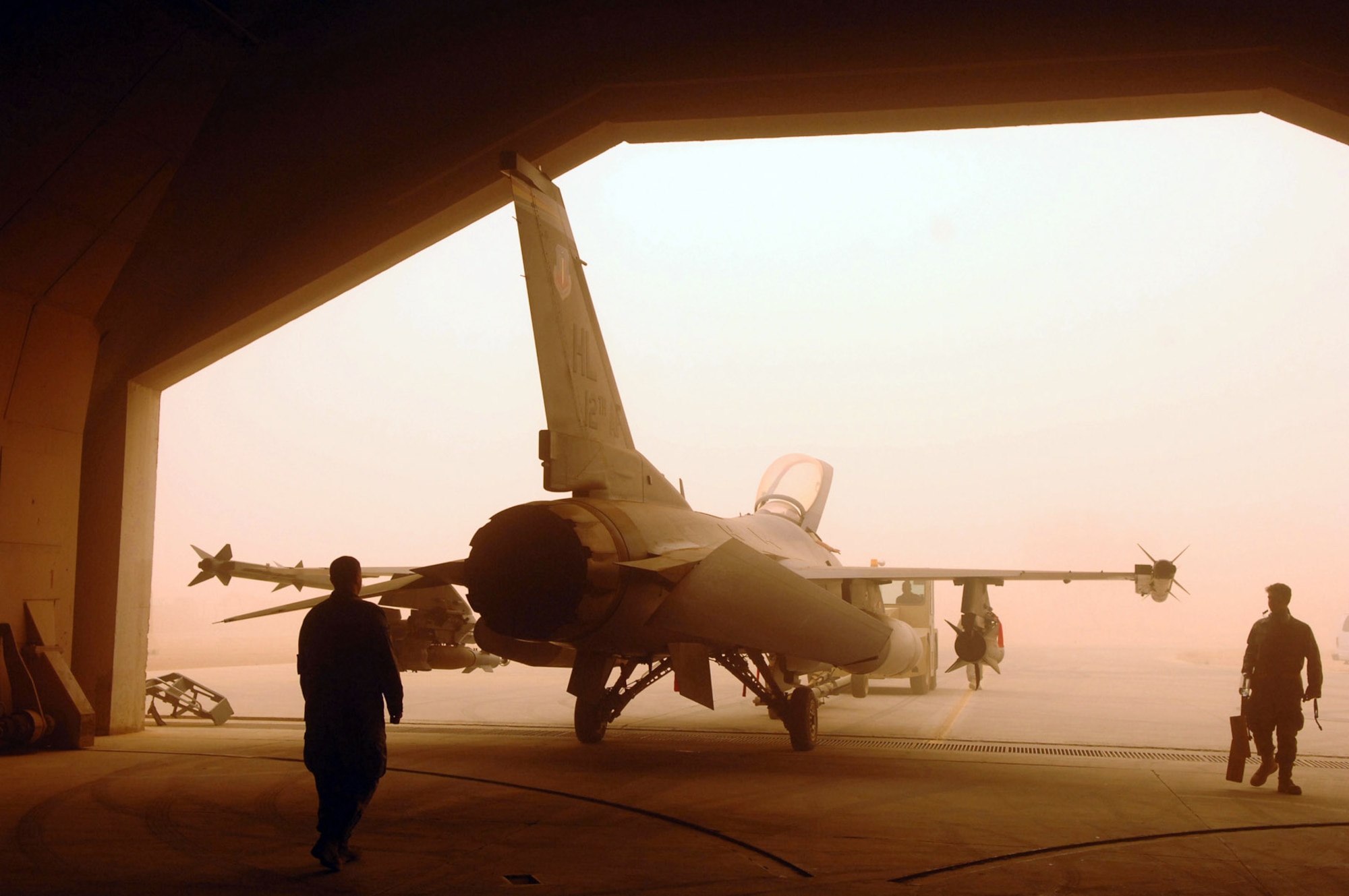 Crew chiefs assigned to the 332nd Expeditionary Aircraft Maintenance Squadron spot an F-16 Fighting Falcon while being pushed into a hardened aircraft shelter during a major dust storm May 9 at Joint Base Balad, Iraq. Protecting flightline assets from dust damage or destruction is important to maintaining the air mission. (U.S. Air Force photo/Senior Airman Julianne Showalter) 
