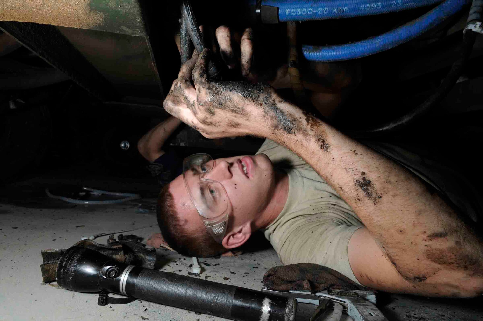 Senior Airman Anthony Dodge applies chaffe wrapping on hydraulic hoses while underneath a hydraulic test stand to prevent hoses from bursting while in operation June 18 at a Southwest Asia air base. Airman Dodge replaces all wrapping due to the wear and tear, intense heat and mechanical vibrations apply to the hoses. Airman Dodge is assigned to the 379th Expeditionary Maintenance Squadron and deployed from MacDill Air Force Base, Fla. (U.S. Air Force photo/Tech. Sgt. Johnny Saldivar) 

