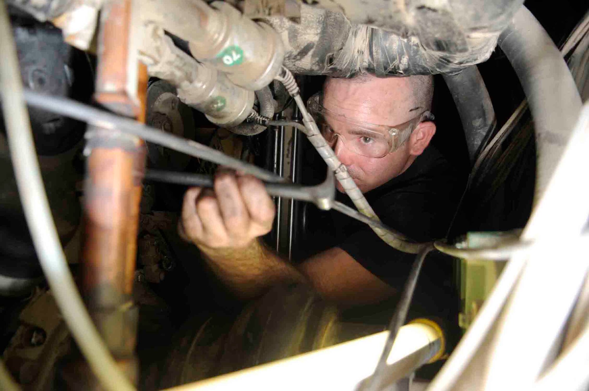 Staff Sgt. Adam R. Tate, 379th Expeditionary Maintenance Squadron, squeezes through a tight space inside of a PD-501 ground cart air conditioner to change a faulty water pump at a Southwest Asia air base June 18. The air conditioning unit cools the inside of an aircraft allowing maintenance crew to perform their duties.  Sergeant Tate is originally from Batesville, Ark. deployed from Whiteman Air Force Base, Mo. (U.S. Air Force photo/Tech. Sgt. Johnny L. Saldivar)