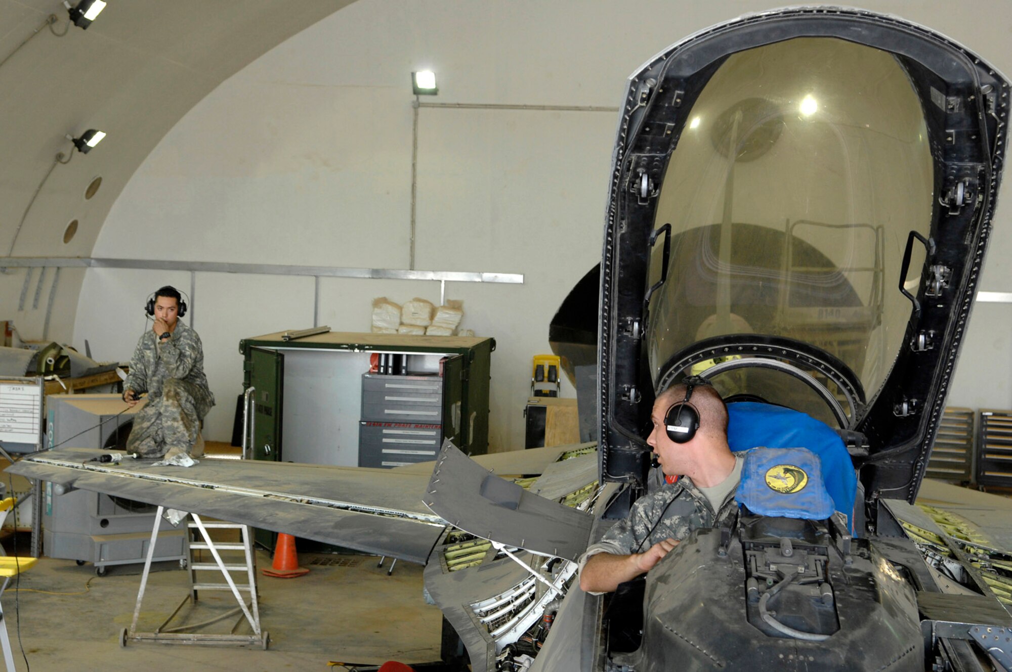 Staff Sgt. Caesar Rivera and Airman 1st Class Shane Bridges communicate back and forth during a test of the leading edge flap as part of a phase inspection on an F-16 Fighting Falcon June 18 at Joint Base Balad, Iraq. The flap is responsible for providing additional lift and drag that is critical for movement at slower air speeds. A phase inspection checks critical aircraft systems to ensure they are in working order and can continue to fly combat missions over Iraq. Sergeant Rivera is deployed from Nellis Air Force Base, Nev., and Airman Bridges is deployed from Shaw AFB, S.C. Both are 332nd Expeditionary Aircraft Maintenance Squadron crew chiefs. (U.S. Air Force photo/Senior Airman Julianne Showalter) 
