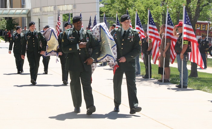 Platoon-mates of fallen soldier, Spc. Daniel Dolan, from Fort Lewis, Wash., escort the covered bronze busts of Spc. Dolan, Sgt. Michael Lehmiller and Cpl. Michael Pursel, as members of the Utah Patriot Guard Riders salute and hold U.S. flags before the unveiling ceremony Saturday, June 21. 