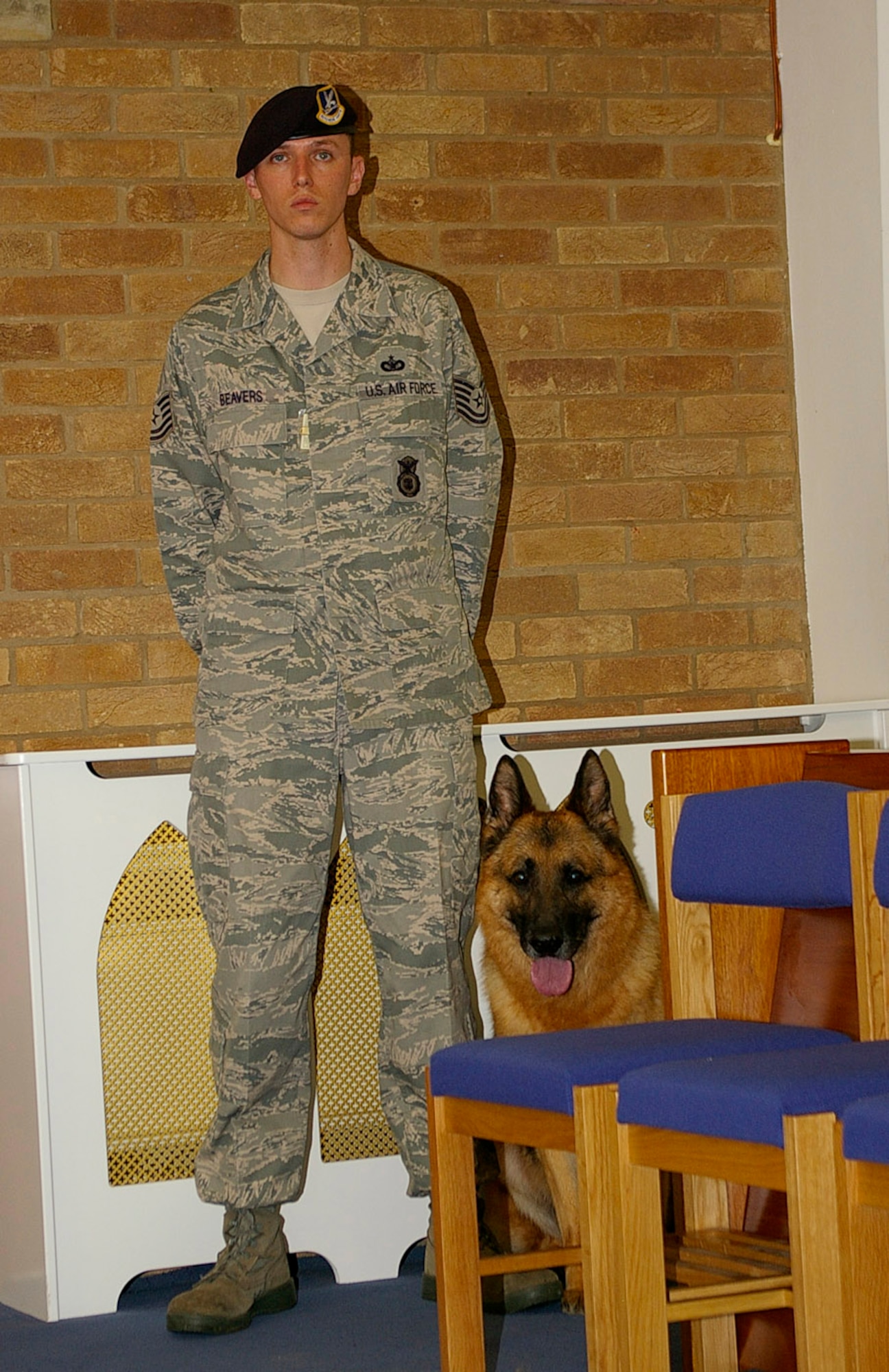 Tech. Sgt. Christopher Beavers, 48th Security Forces Squadron Military Working Dog handler, and his partner, MWD Whisky, listen as MWD War's biography is read out during a memorial service June 23 at RAF Mildenhall Chapel. Military working dogs and their handlers from both RAFs Mildenhall and Lakenheath attended War's ceremony to pay their respects to their former comrade. (U.S. Air Force photo by Karen Abeyasekere)