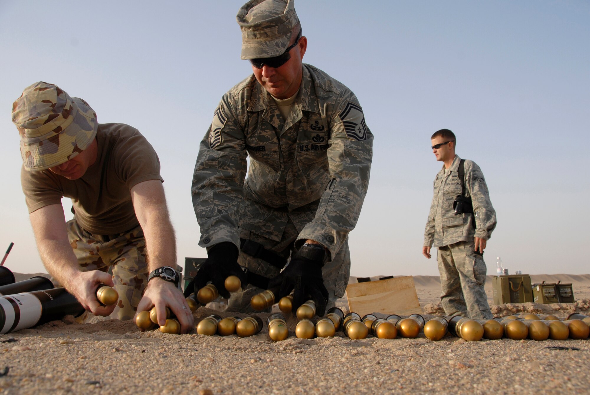 SOUTHWEST ASIA -- Australian Army ammunition technician Warrant Officer Class Two Neil Snape (left), Senior Master Sgt. Russell Corner (center), and Senior Airman Charles Howell, both from the 386th Expeditionary Civil Engineer Squadron explosive ordnance disposal flight, help move 40 millimeter high explosive dual purpose rifle grenades for disposal during a controlled detonation June 20, 2008, at an EOD range in the Persian Gulf Region.  The joint detonation also provided an opportunity for the coalition forces to enhance relations while learning some of the slight differences in operating procedures. (U.S. Air Force photo/ Staff Sgt. Patrick Dixon)