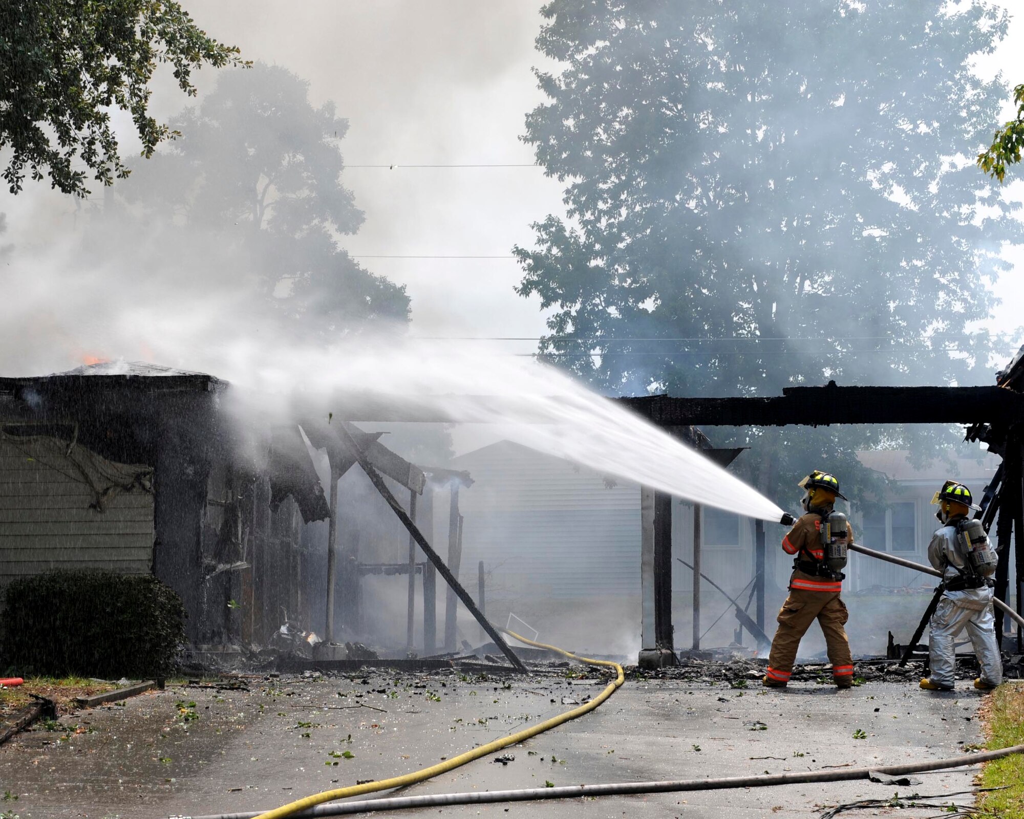 SHAW AIR FORCE BASE, S.C.-- Two Shaw firefighters douse flames that have eaten away at two houses here June 20. The house is in an area marked for demolition and was not occupied. (U.S. Air Force Photo/Staff Sgt. Henry Hoegen)