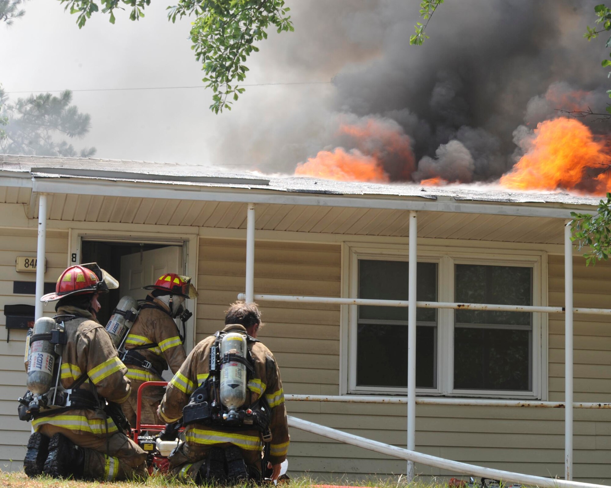 SHAW AIR FORCE BASE, S.C.-- Two Shaw firefighters rest and watch as another firefighter continues inside to suppress the flames June 20. The house is in an area marked for demolition and was not occupied. (U.S. Air Force Photo/Staff Sgt. Henry Hoegen)