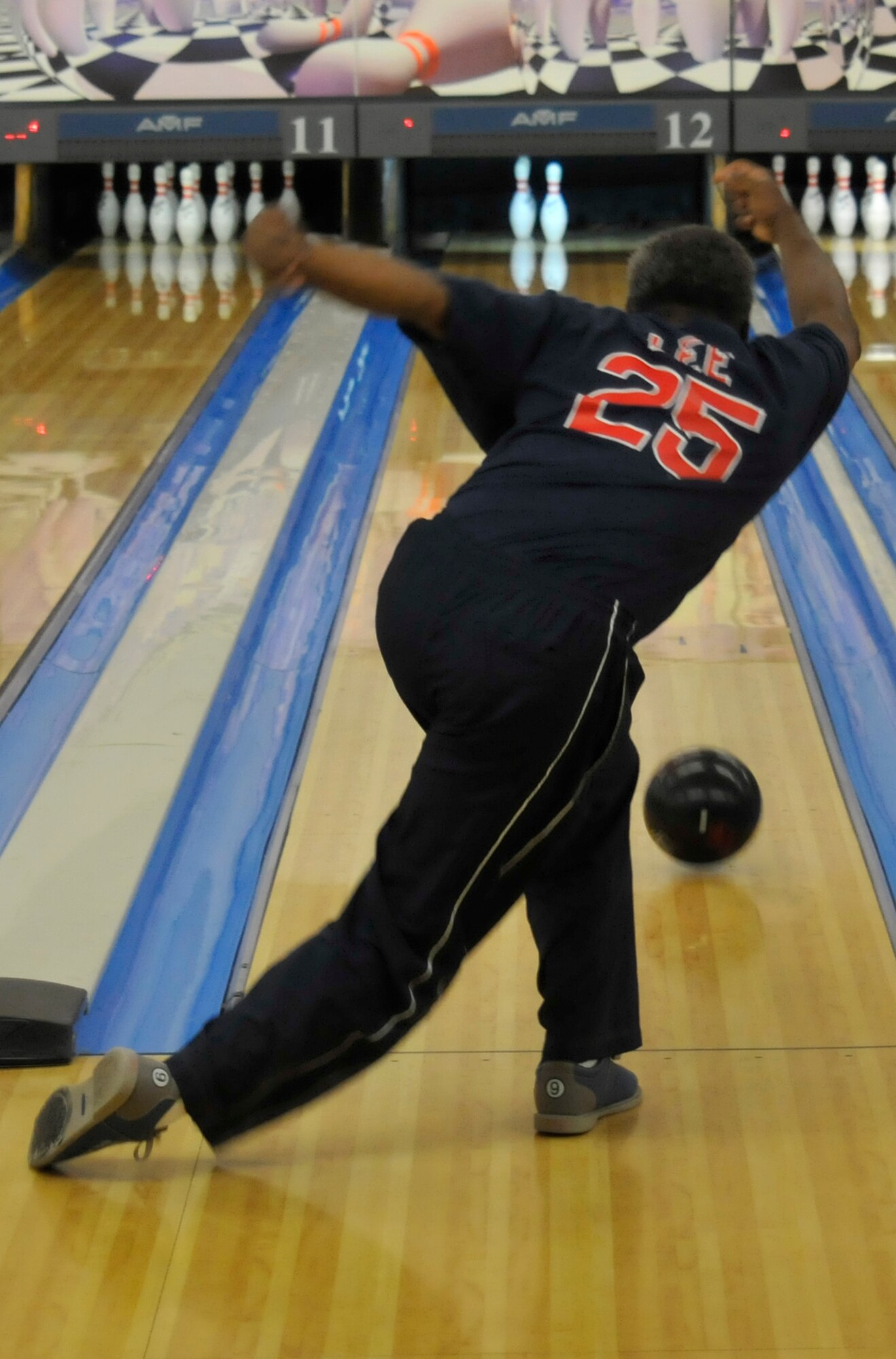 A 21st Space Wing member lets it roll down the alleyway while competing in bowling during Sports Day activities June 19 at Peterson Air Force Base, Colo. Sports Day is an annual event that gives members of the wing time to build teamwork skills and boost morale. The event also offers the wing a chance to flex its “Fit to Fight” muscles. (U.S. Air Force photo/Larry Hulst)