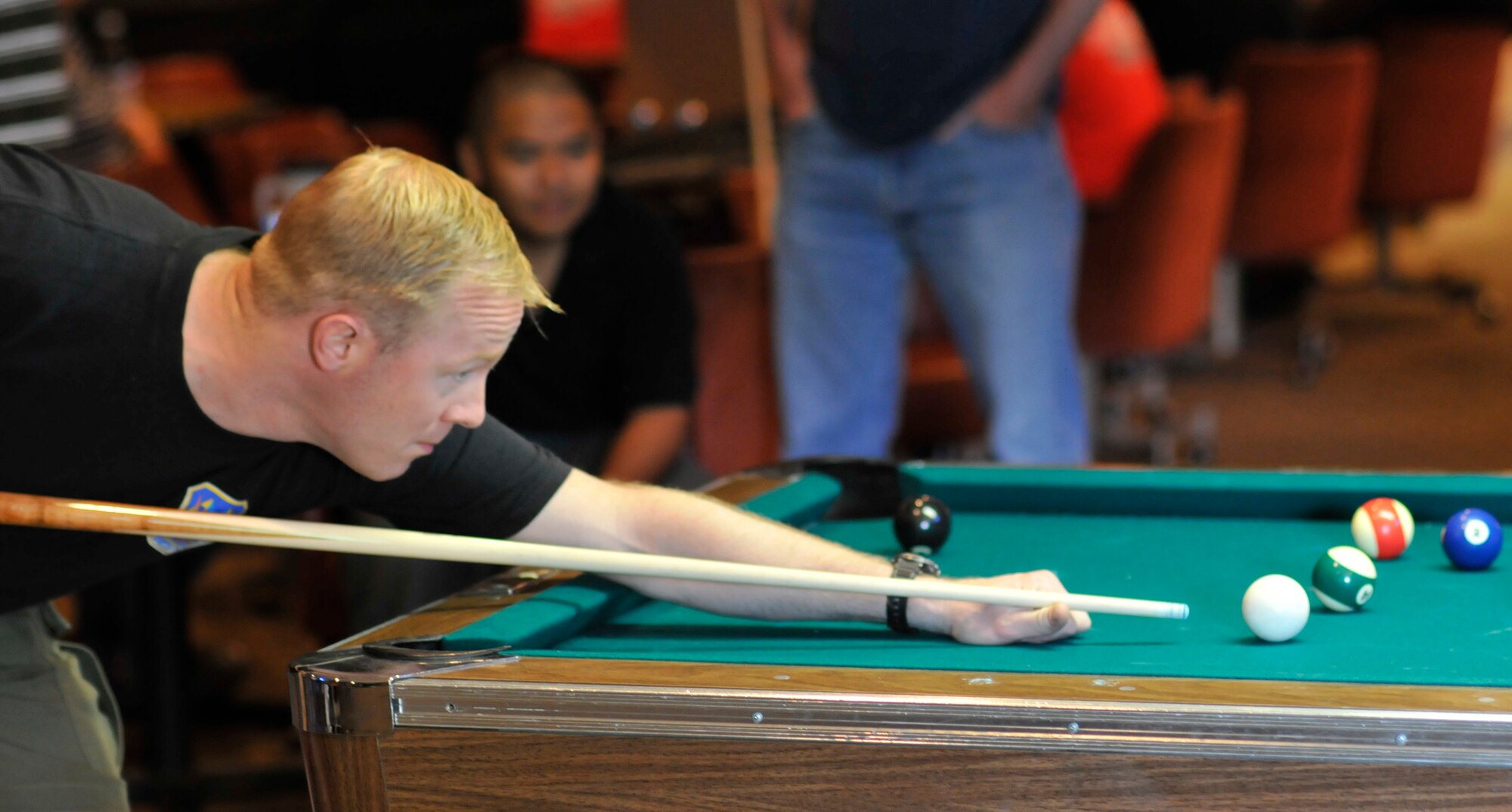 A 21st Space Wing member looks for a corner pocket shot while playing billiards during Sports Day activities June 19 at Peterson Air Force Base, Colo. Sports Day is an annual event that gives members of the wing time to build teamwork skills and boost morale. The event also offers the wing a chance to flex its “Fit to Fight” muscles. (U.S. Air Force photo/Larry Hulst)