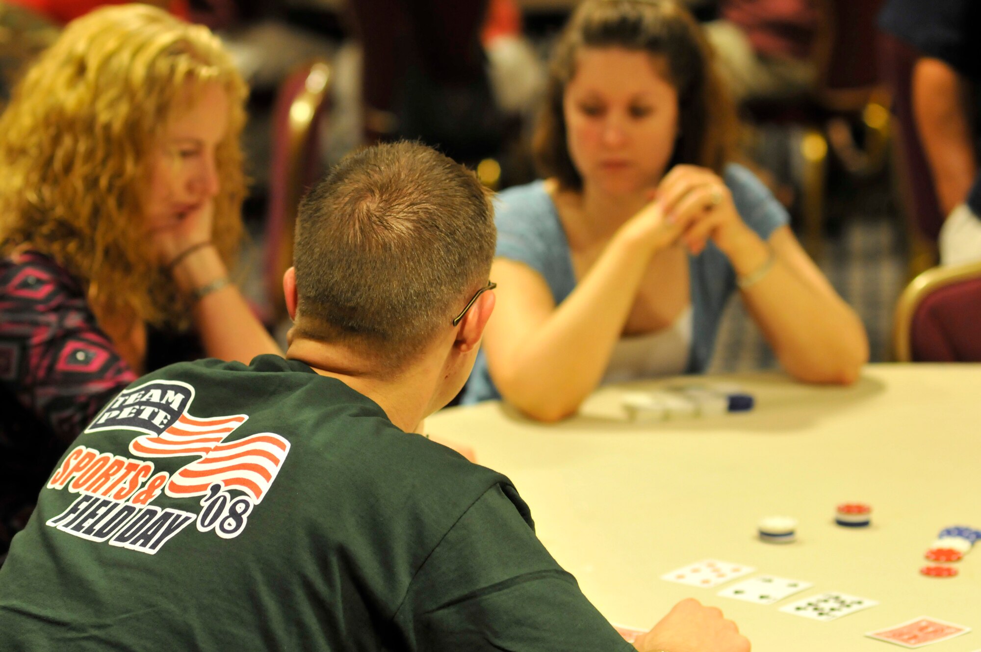 Members of the 21st Space Wing eye each other’s hand while playing Texas Hold ‘Em poker during Sports Day activities June 19 at Peterson Air Force Base, Colo.  Sports Day is an annual event that gives members of the wing time to build teamwork skills and boost morale. The event also offers the wing a chance to flex its “Fit to Fight” muscles. (U.S. Air Force photo/Larry Hulst)