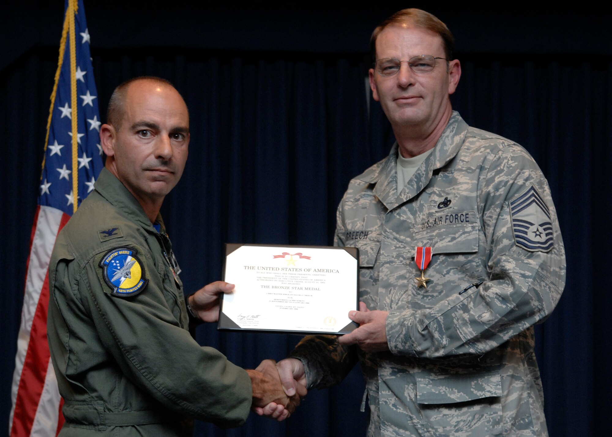 Chief Master Sgt. David Creech, 49th Maintenance Squadron, receives his Bronze Star Medal certificate from Col. Jeff Harrigian, 49th Fighter Wing commander during Warrior Call, June 20 at the Desert Sands Enlisted Club at Holloman Air Force Base, N.M. The Bronze Star Medal is the 9th highest military award, including both combat and non-combat awards, in the order of precedence of U.S. military decorations. (U.S. Air Force photo/Airman 1st Class Rachel A. Kocin)