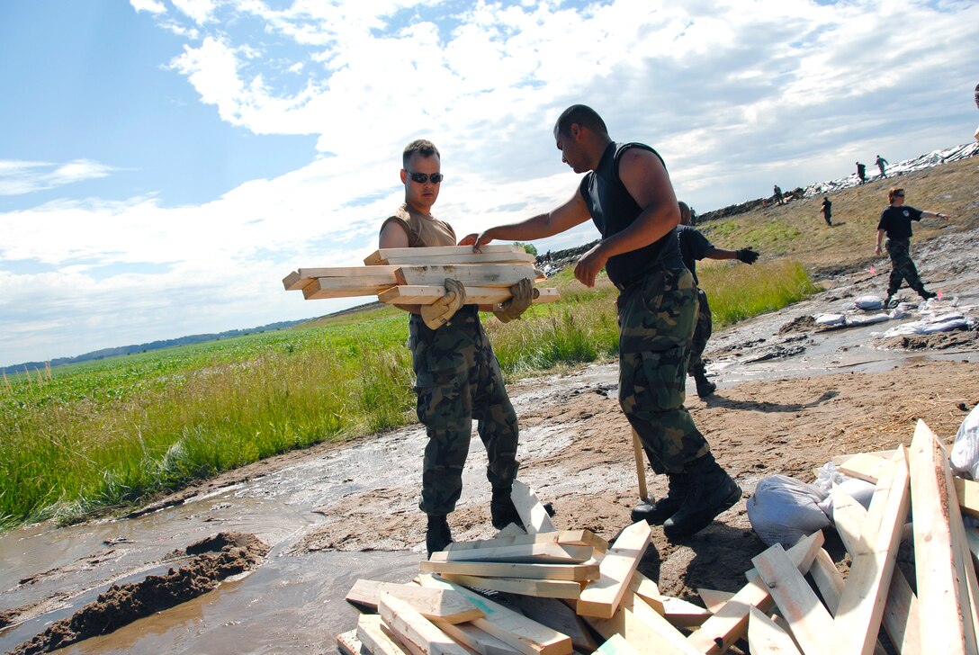 U.S. Air Force Airman 1st Class Jordan Kelson hands Tech. Sgt. Daniel Griego stakes of wood to reinforce the Indian Graves levee in Quincy, Ill., June 22, 2008. Both men are assigned to the Illinois Air National Guard.