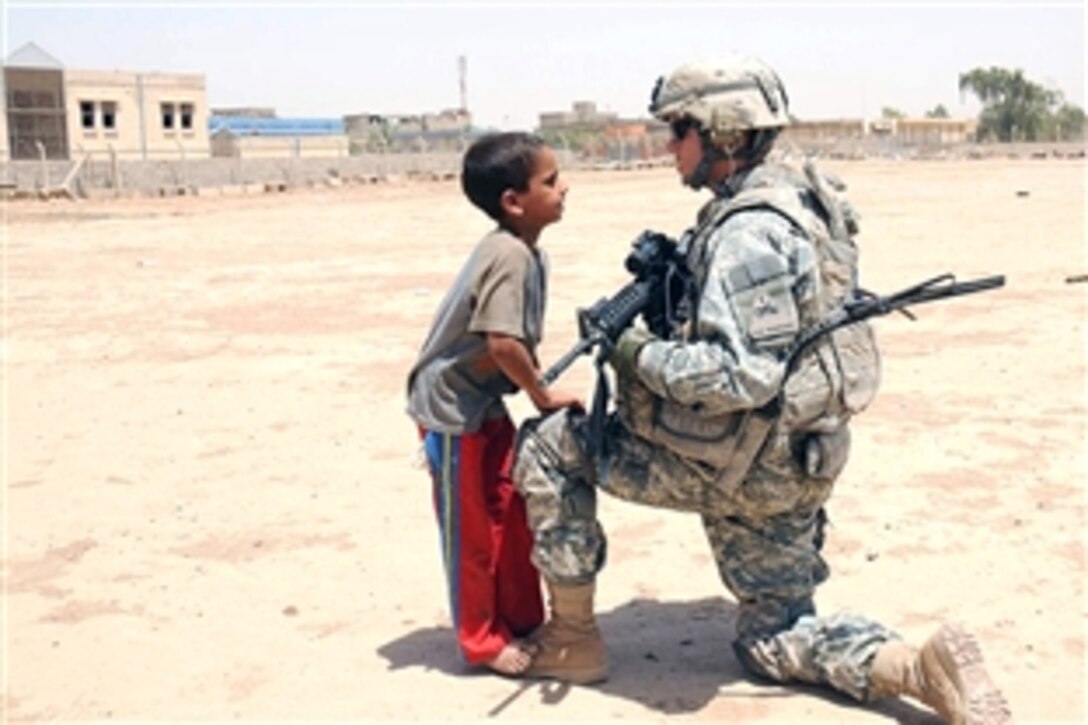 U.S. Army Staff Sgt. Fred Hampton kneels on a knee to talk with a young Iraqi boy at the future site of a park in the Thawra 1 neighborhood of the Sadr City district of Baghdad on June 20, 2008. Hampton is assigned to the 1st Battalion, 6th Infantry Regiment, Task Force Regulators. 