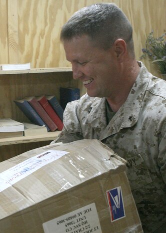 Navy Lt. Joel Degraeve, the chaplain with Task Force 2nd Battalion, 2nd Marine Regiment, Regimental Combat Team 5, carries a package sent by the newly instituted Parent Network of the battalion at Camp Al Qa'im, Iraq, June 23. The network started shortly before the battalion's deployment to western Al Anbar province and continues to expand all over the United States. The network, which has over 1,000 parents of Marines with 2nd Bn., 2nd Marines, provides a way for parents to obtain information on their Marines.