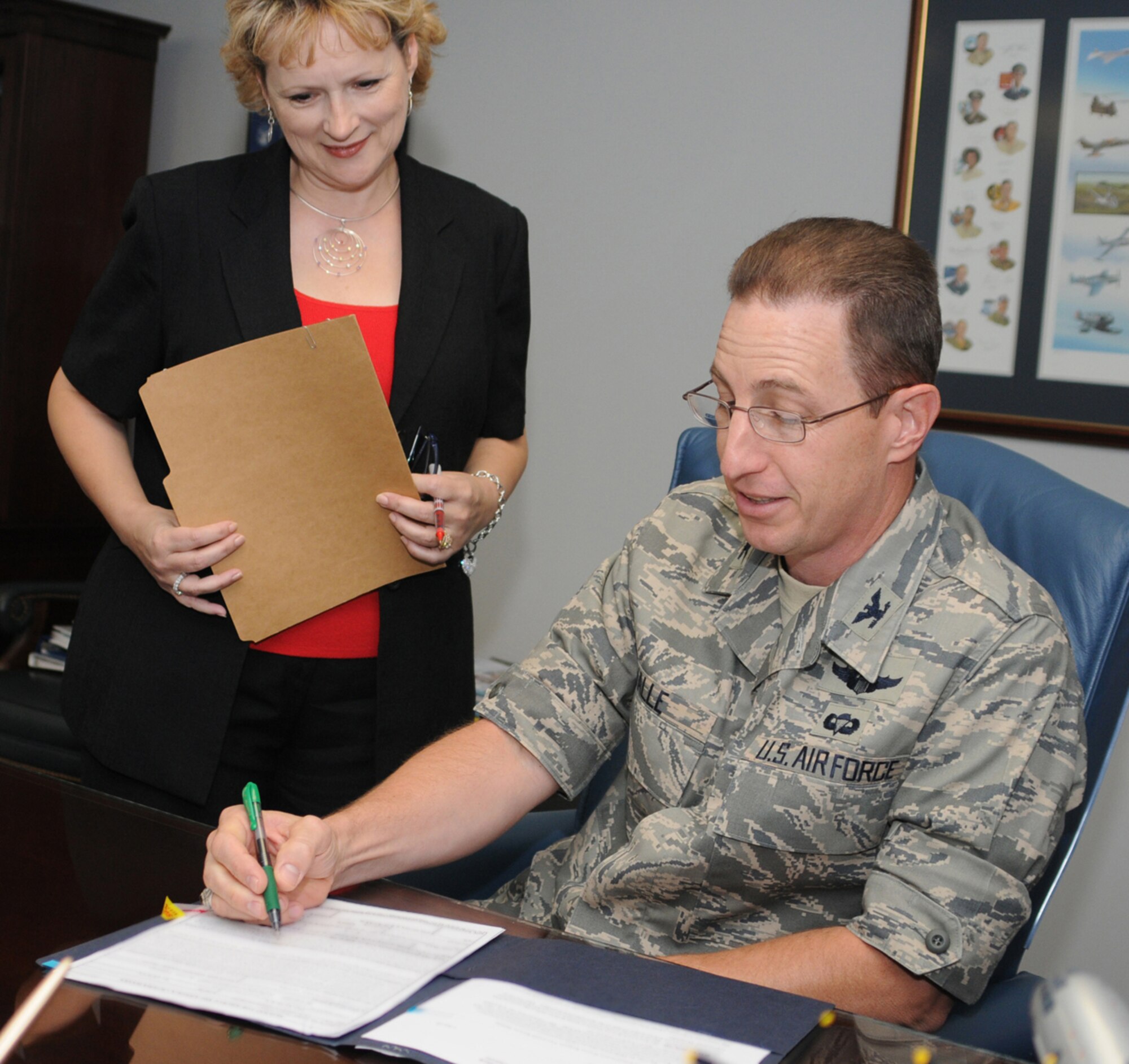 Melva Kroll, secretary to the 81st Training Wing vice commander, brings documents for signature to her new boss, Col. Christopher Valle.  Colonel Valle, an Air Force Academy graduate, is a command pilot with more than 4,200 flying hours in the C-141B, C-20A and C-21A.  His last assignment was at Scott Air Force Base, Ill., where he completed a joint tour in U.S. Transpor-tation Command, serving as airlift team/industry branch chief and executive officer to the deputy commander.  (U.S. Air Force photo by Kemberly Groue)