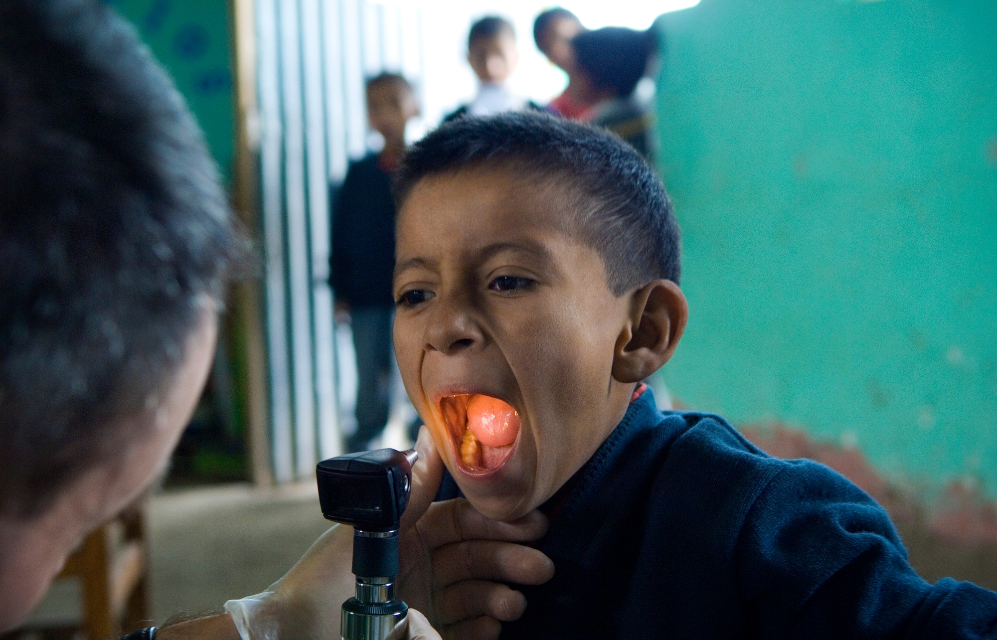Maj. Eric Potwardowski checks the tonsils of a Peruvian child during free medical examinations June 22 inside a local school house in Ayacucho, Peru. American servicemembers are providing medical care during New Horizons-Peru 2008, a U.S. and Peruvian partnered humanitarian mission set on providing relief to underprivileged Peruvians. Major Potwardowski is deployed from the 452nd Medical Squadron at March Air Reserve Base, Calif. (U.S. Air Force photo/Staff Sgt. Bennie J. Davis III)