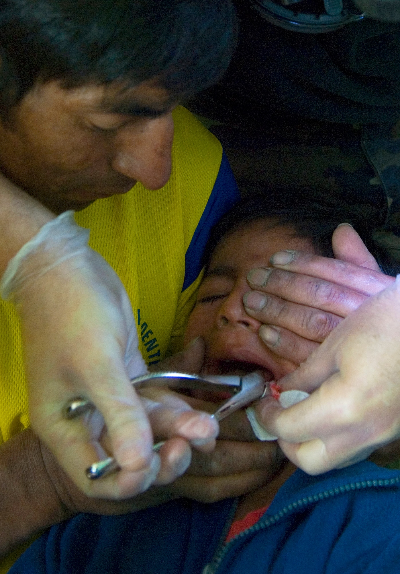 A Peruvian father holds his son tight while Maj. Brad Duper extracts a cavity filled tooth in a make-shift dental office June 22 inside a local schoolhouse in Ayacucho, Peru. American servicemembers are providing medical care during New Horizons-Peru 2008, a U.S. and Peruvian partnered humanitarian mission set on providing relief to underprivileged Peruvians. Major Duper is a dentist with the 452nd Aeromedical-Dental Squadron at March Air Reserve Base, Calif. (U.S. Air Force photo/Staff Sgt. Bennie J. Davis III)