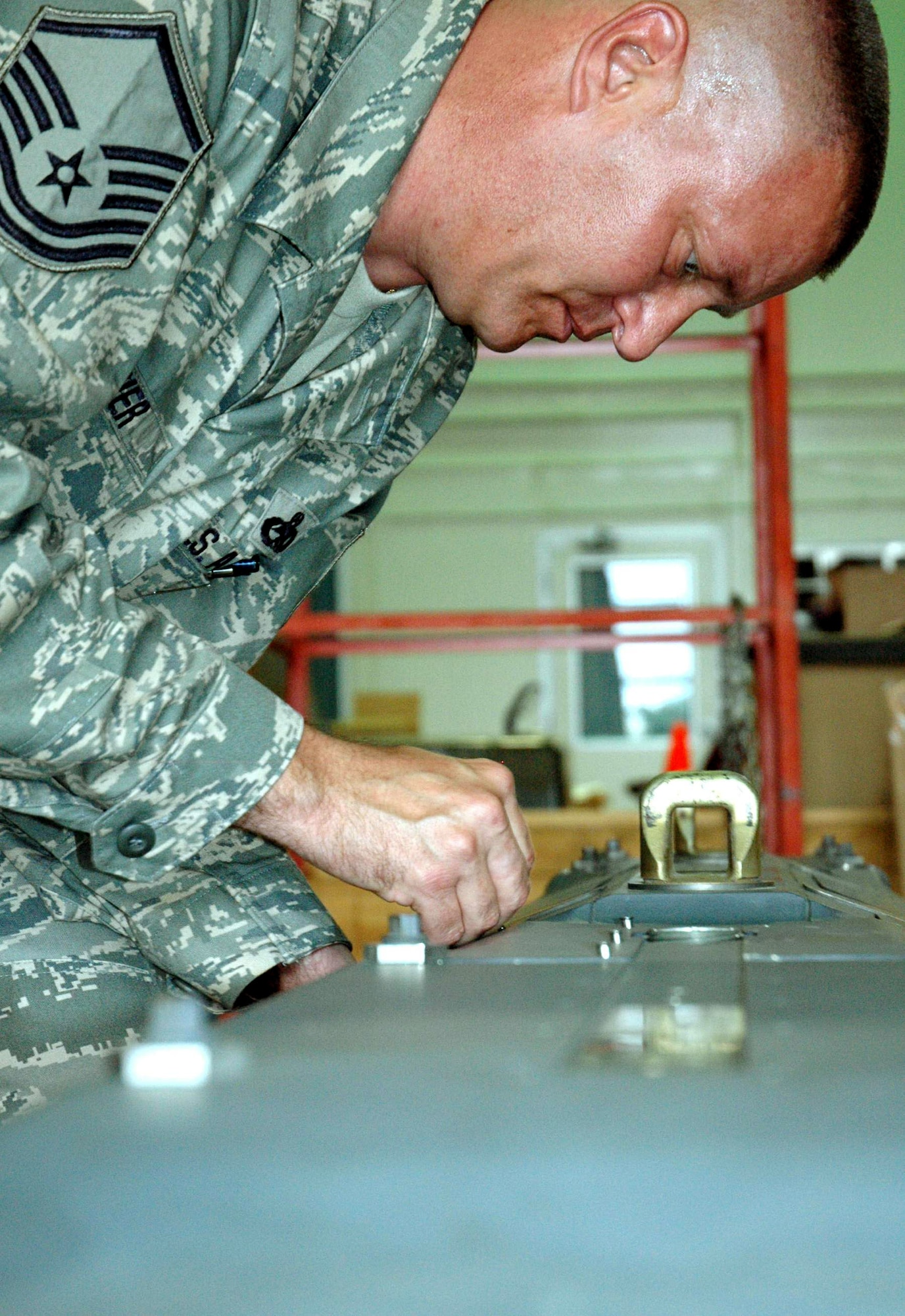 Master Sgt. Brian Mosier tightens the screws to hold the cover of the pneumatic carriage system that holds and discharges the Small Diameter Bombs June 2 at Eglin Air Force Base, Fla. Sergeant Mosier is assigned to the 681st Armament Systems Squadron Small Diameter Bomb logistics team. (U.S. Air Force photo/Staff Sgt. Stacia Zachary) 
