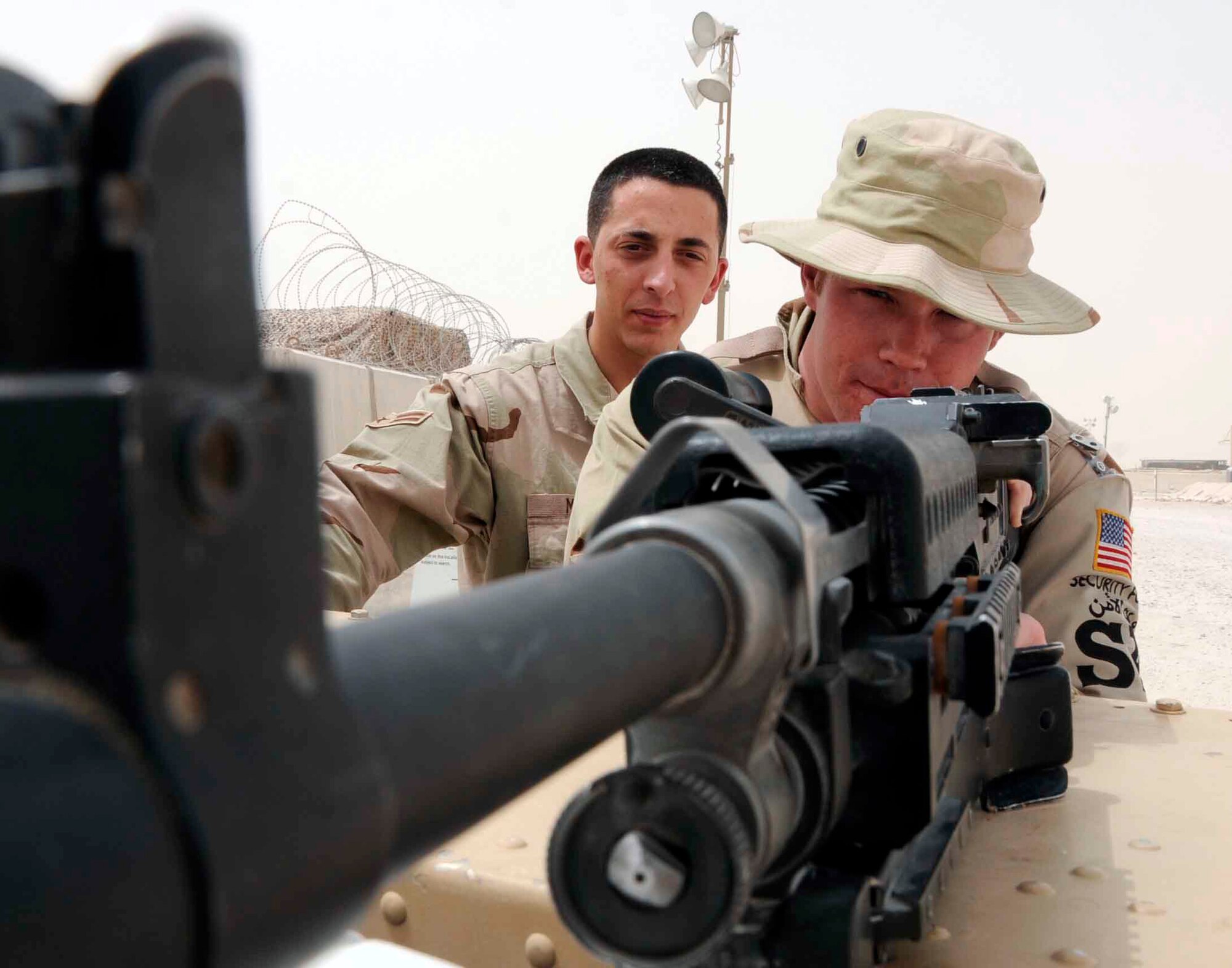 Airman 1st Class David Metter instructs Air Force Academy Cadet Brian Gilliam June 17 on the proper handling of a M240B machine gun at a base in Southwest Asia. Cadet Gilliam supports the weight of the gun on the back of a humvee near the entry control point to the flightline. The cadets are visiting the base as part of the academy's Operation Air Force program, allowing them to experience an active-duty deployment. (U.S. Air Force photo/Senior Airman Domonique Simmons) 
