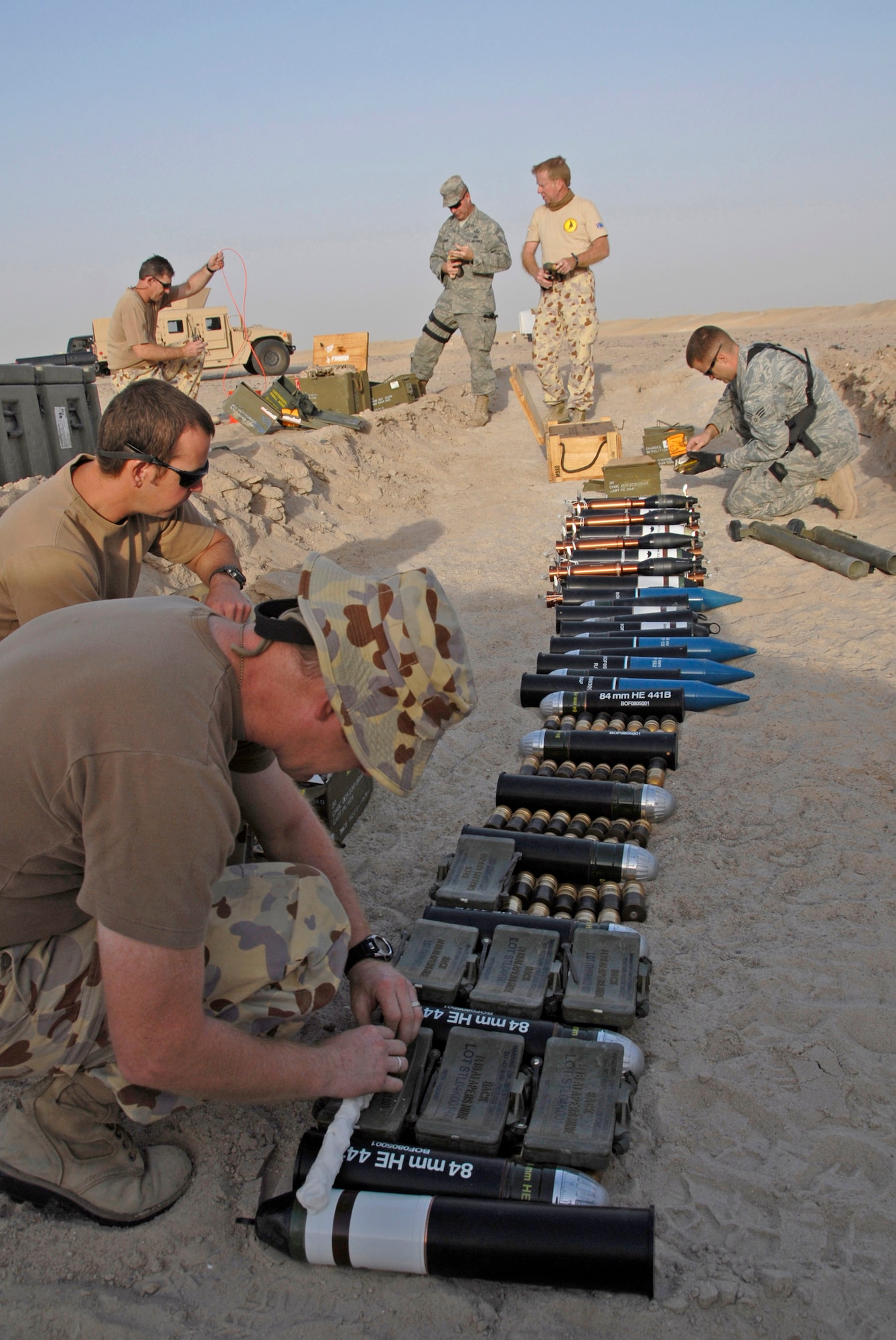 Australian army ammunition technicians and members from the 386th Expeditionary Civil Engineer Squadron Explosive Ordnance Disposal Flight lay down plastic explosive over munitions during a controlled detonation June 20 at an EOD range in Southwest Asia. The joint detonation also provided an opportunity for the coalition forces to enhance relations while learning some of the slight differences in operating procedures. (U.S. Air Force photo/Staff Sgt. Patrick Dixon) 
