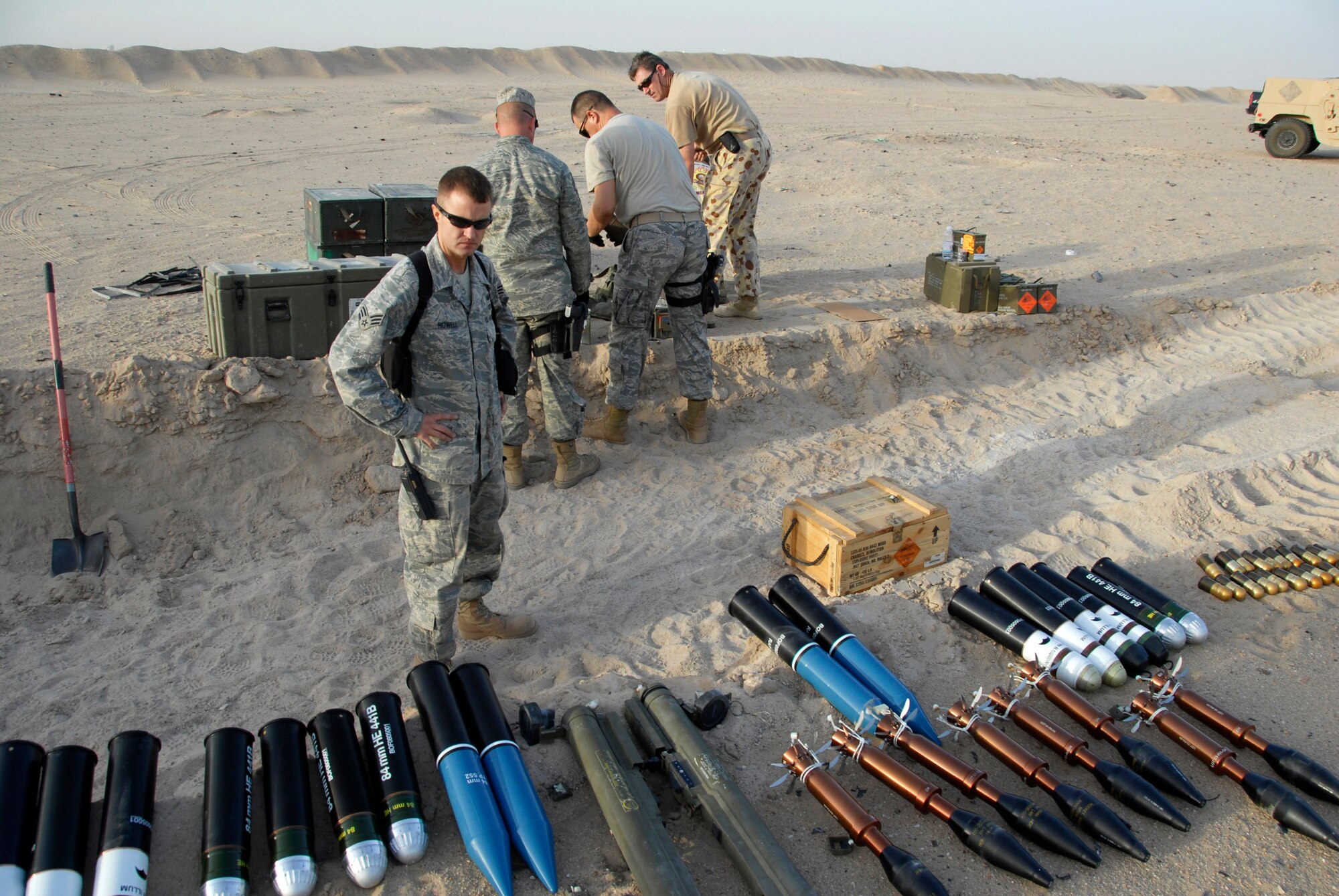 Senior Airman Charles Howell (front center) looks over the munitions that are about to be destroyed while other Airmen and Australian army ammunition technicians prepare light anti-armor weapon rockets for disposal prior to a controlled detonation June 20 at an explosive ordnance disposal range in Southwest Asia. The joint detonation also provided an opportunity for the U.S. and coalition forces to enhance their relations while learning some of the slight differences in operating procedures. Airman Howell is assigned to the 386th Expeditionary Civil Engineer Squadron Explosive Ordnance Disposal Flight. (U.S. Air Force photo/Staff Sgt. Patrick Dixon) 
