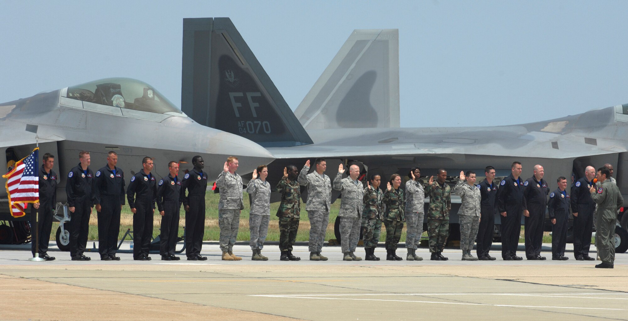 LANGLEY AIR FORCE BASE, Va. - Maj. Paul "Max" Moga, the first F-22A Raptor Demonstration Team pilot, leads 10 Langley Airmen in the re-enlistment oath during a ceremony here at AirPower over Hampton Roads June 22. With the re-enlistment, the Airmen volunteered to serve another four or six years in the Air Force. (U.S. Air Force photo/Airman 1st Class Gul Crockett)