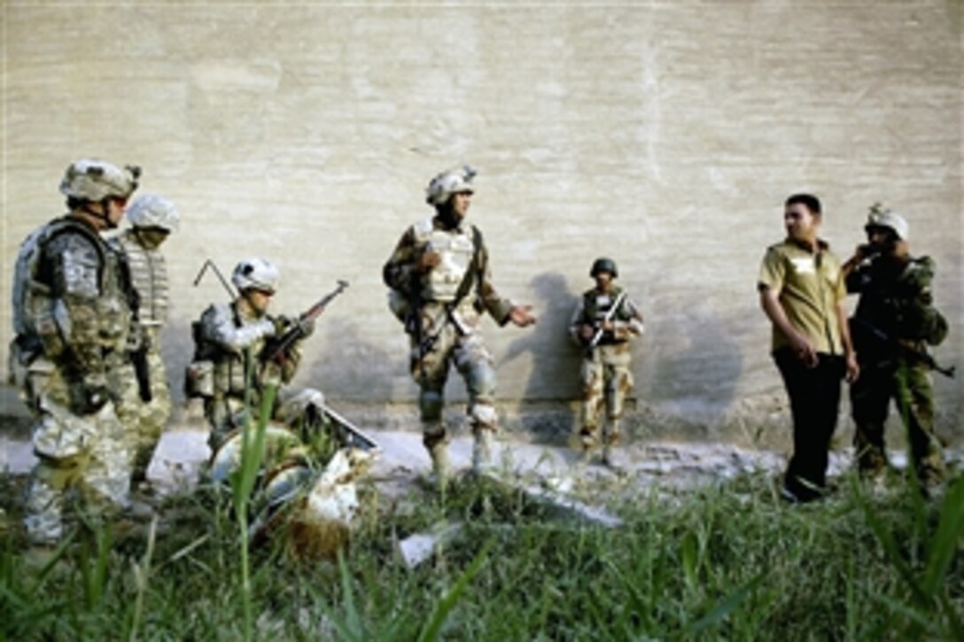 Iraqi army soldiers watch as U.S. Army soldiers check an AK-47 handed off to them by the owner during a joint patrol conducting a weapons search in Shulla, Iraq, June 19, 2008. 