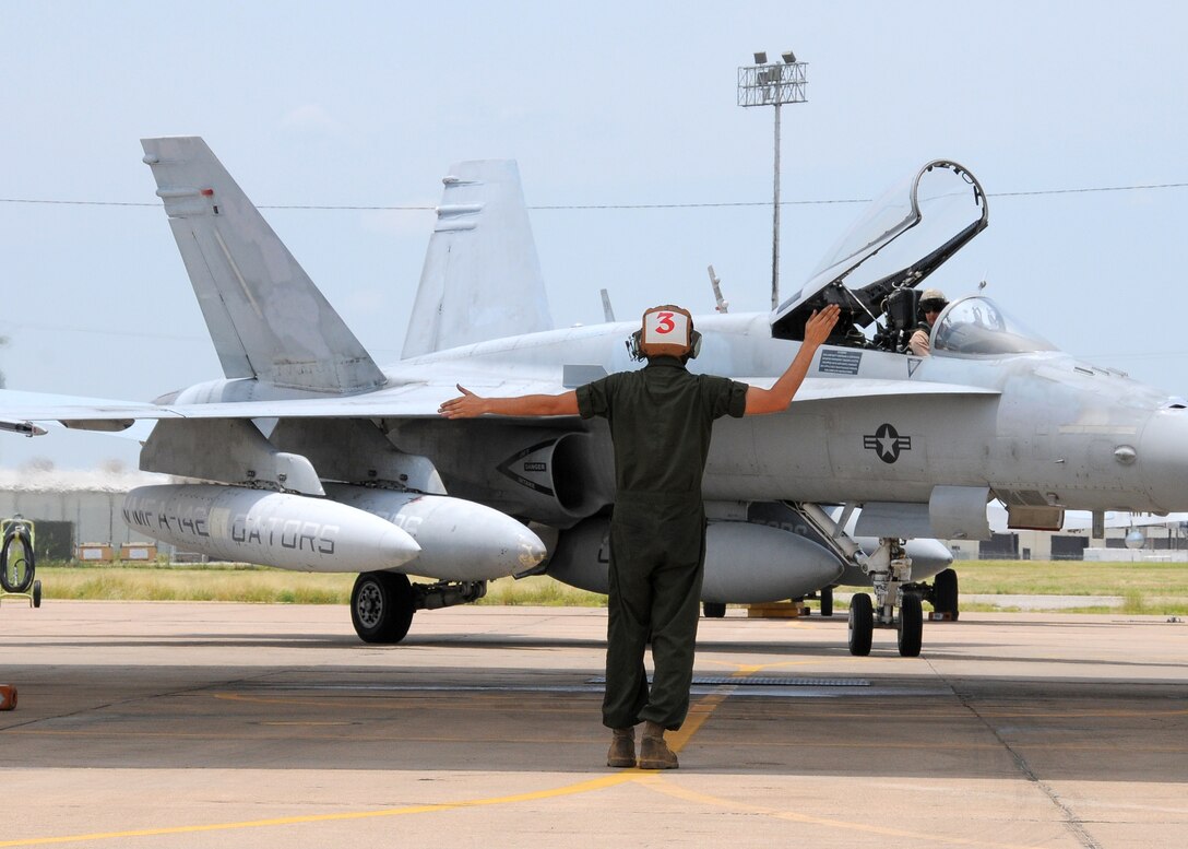 A plane captain from Marine Fighter Attack Squadron 112 directs the pilot of one of the two F/A-18 Hornets Marine Aircraft Group 41 received from VMFA-142 on June 24. The squadron colors of the VMFA-142 "Gators" were cased and transitioned to MAG-41 following the June 21 decommissioning of Atlanta-based MAG-42.