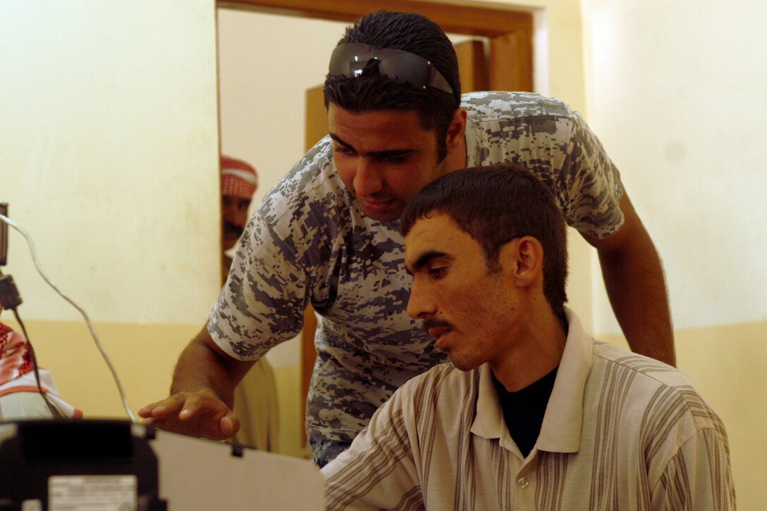 FALLUJAH, IRAQ An Iraqi Police officer helps a Fallujah resident in the process of receiving a new badge during a remote badging operation here, June 25. The operation was performed after 3rd Battalion, 6th Marines noticed a trend of expired IDs in southern Fallujah. Residents need a current ID to gain access in and out of the city. (Official U.S. Marine Corps photo by Cpl. Chris Lyttle) (RELEASED)