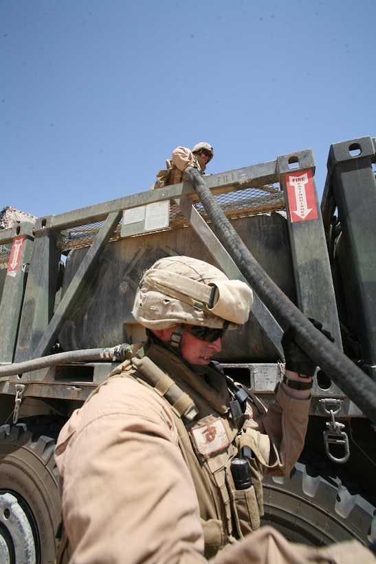 Sergeant Barnaby E. Yoder, a motor transport operator, passes a gas hose up to Sgt. Greg G. Mosher, motor transport chief, to refuel a vehicle at Camp Hit, Iraq, July 1.   Both Marines are with Task Force Hit, 3rd Battalion, 4th Marine Regiment, Regimental Combat Team 5.  Marines in Motor T have traveled long distance throughout the battalionâ??s area of operations, which measures more than 2,600 miles. Despite the long days, the Marines have stayed motivated because they know they are helping the infantry Marines.::r::::n::