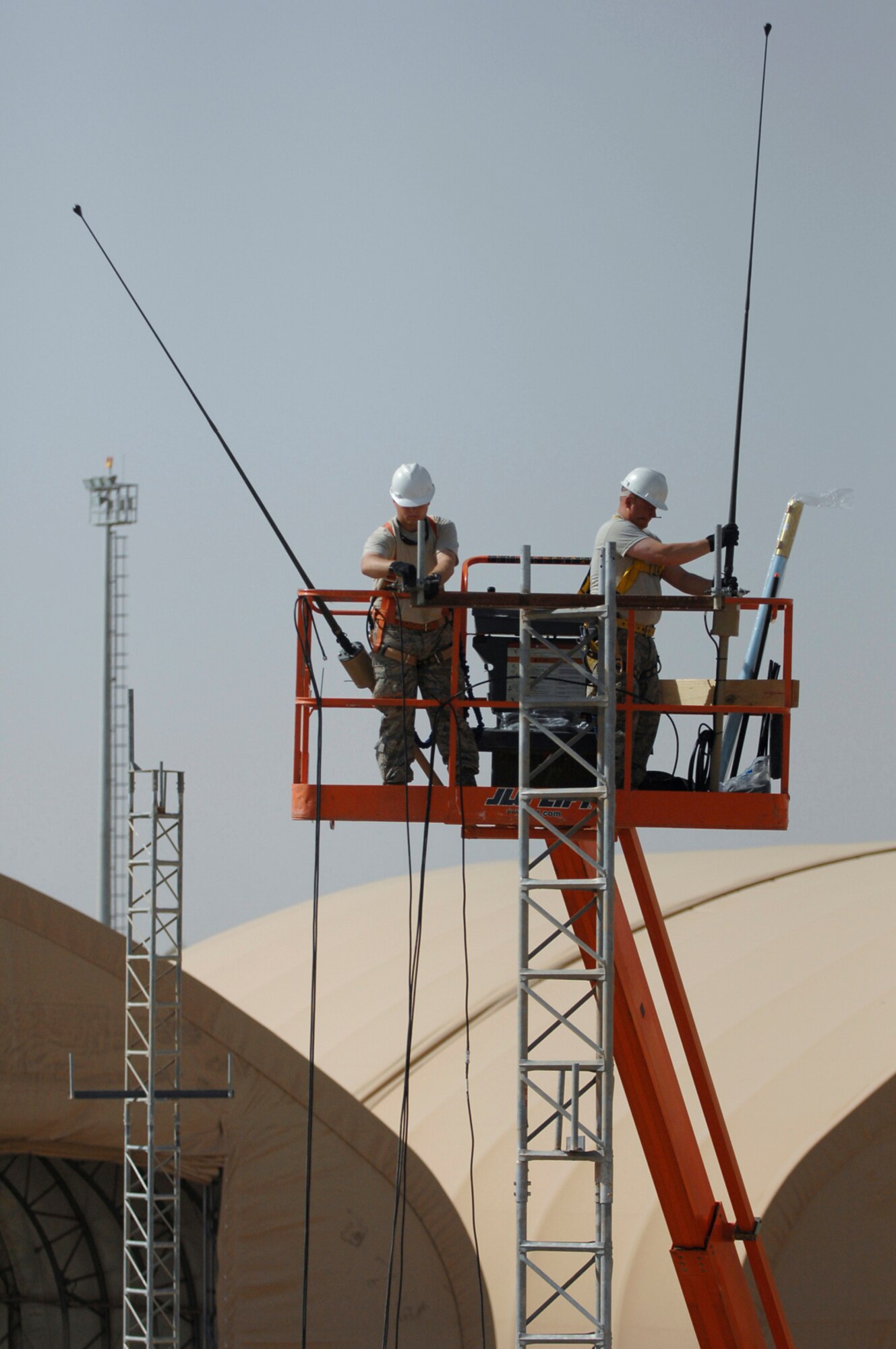 JOINT BASE BALAD, Iraq -- Senior Airman Paul Martin and Tech. Sgt. Robert Fisher, 332nd Expeditionary Communications Squadron ground radio maintainers, install very high frequency radio antennas which will be used for future ground to air tactical radio communications and provide more land mobile radio capabilities for ground operations here, June 21. Airman Martin is deployed from Yokota Air Base, Japan, and Sergeant Fisher is deployed from Youngstown Air Reserve Base, Ohio. (U.S. Air Force photo/ Senior Airman Julianne Showalter)