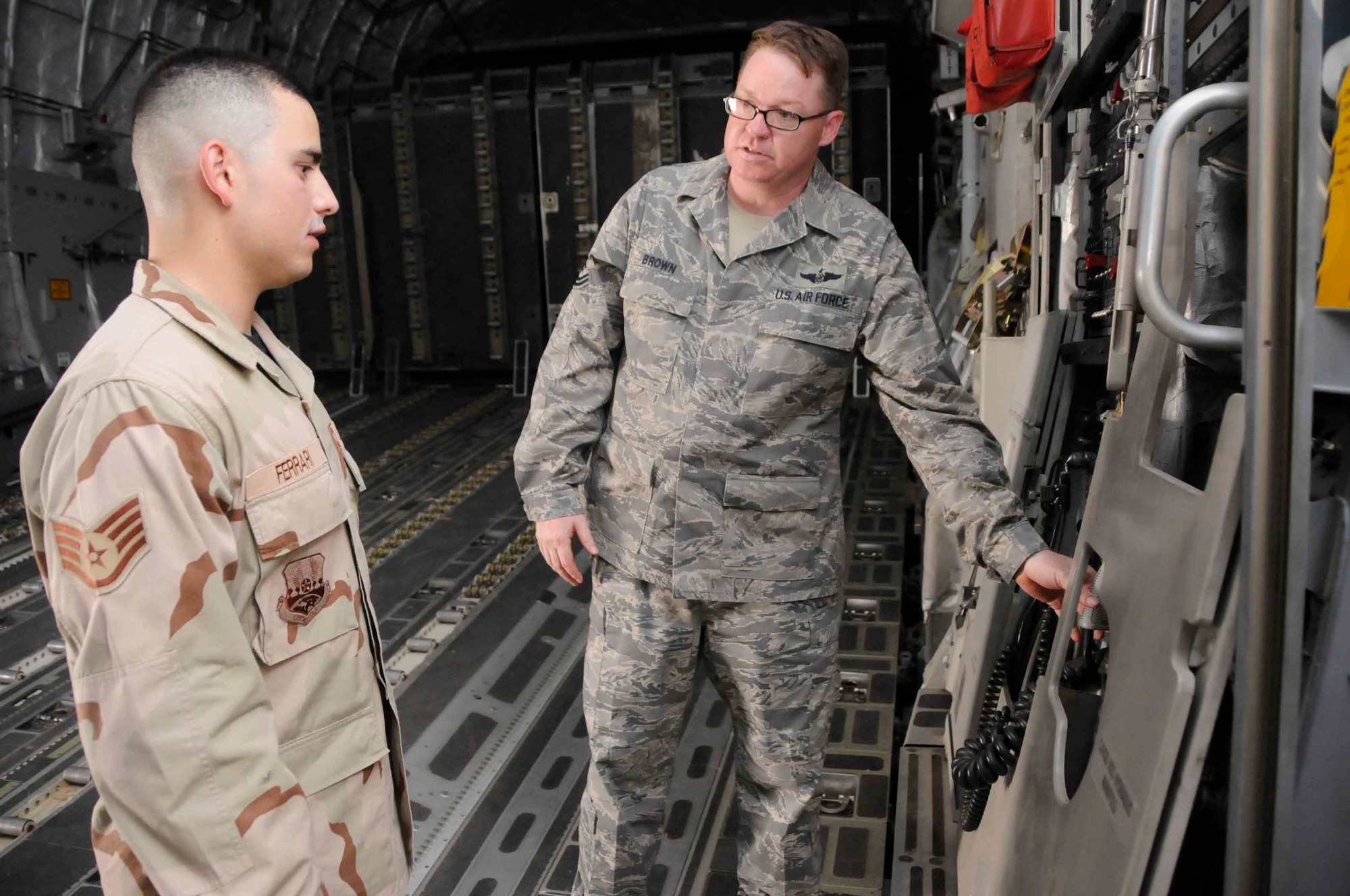 SOUTHWEST ASIA--Master Sgt. Will Brown, 816th Expeditionary Airlift Squadron, shows Staff Sgt. Enzzo Ferrari some of the tasks of a C-17 loadmaster June 24. Sergeant Ferrari is interested in cross-training from the 379th Expeditionary Operations Support Squadron. (U.S. Air Force photo/Senior Airman Domonique Simmons)