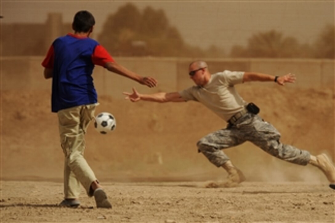 U.S. Air Force Senior Airman Charles Woford from the 447th Air Expeditionary Group Chapel stretches to block a shot by a local Iraqi child at Sather Air Base, Iraq, during a game of soccer on June 6, 2008.  Woford is one of a group of airmen who delivered toys and gifts donated by the airmen assigned to Sather Air Base.  