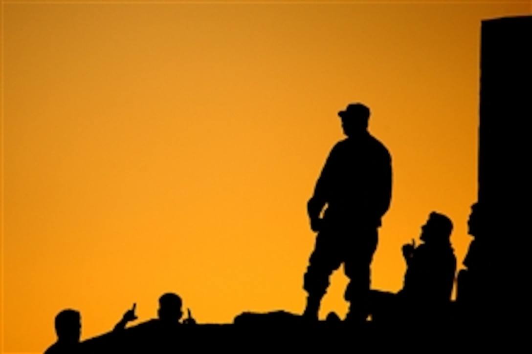 Members of the Iraqi Air Force, perched atop a bunker, watch U.S. and Iraqi airmen compete against each other in a soccer match at New Al Muthana Air Base, Iraq, June 20, 2008. The match was hosted by the Coalition Air Force Training Team. 