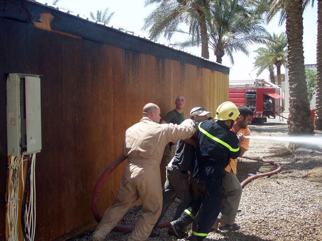 FALLUJAH, Iraq (June 25, 2008) â?? Captain Jeremy Anzevino, company commander, 3rd Battalion, 6th Marines and Fallujah firefighters use a hose to fight the fire that destroyed the Marine compound at Entry Control Point-5 (ECP-5), June 25. The fire spread throughout the post and burned down every wooden hut, leaving most of the Marines without equipment or personal possessions. The company said it has received generous support from local Iraqis, neighboring units and stateside supporters to recover from this incident. (Official U.S. Marine Corps photo by Company L, 3rd Battalion, 6th Marines) (RELEASED)