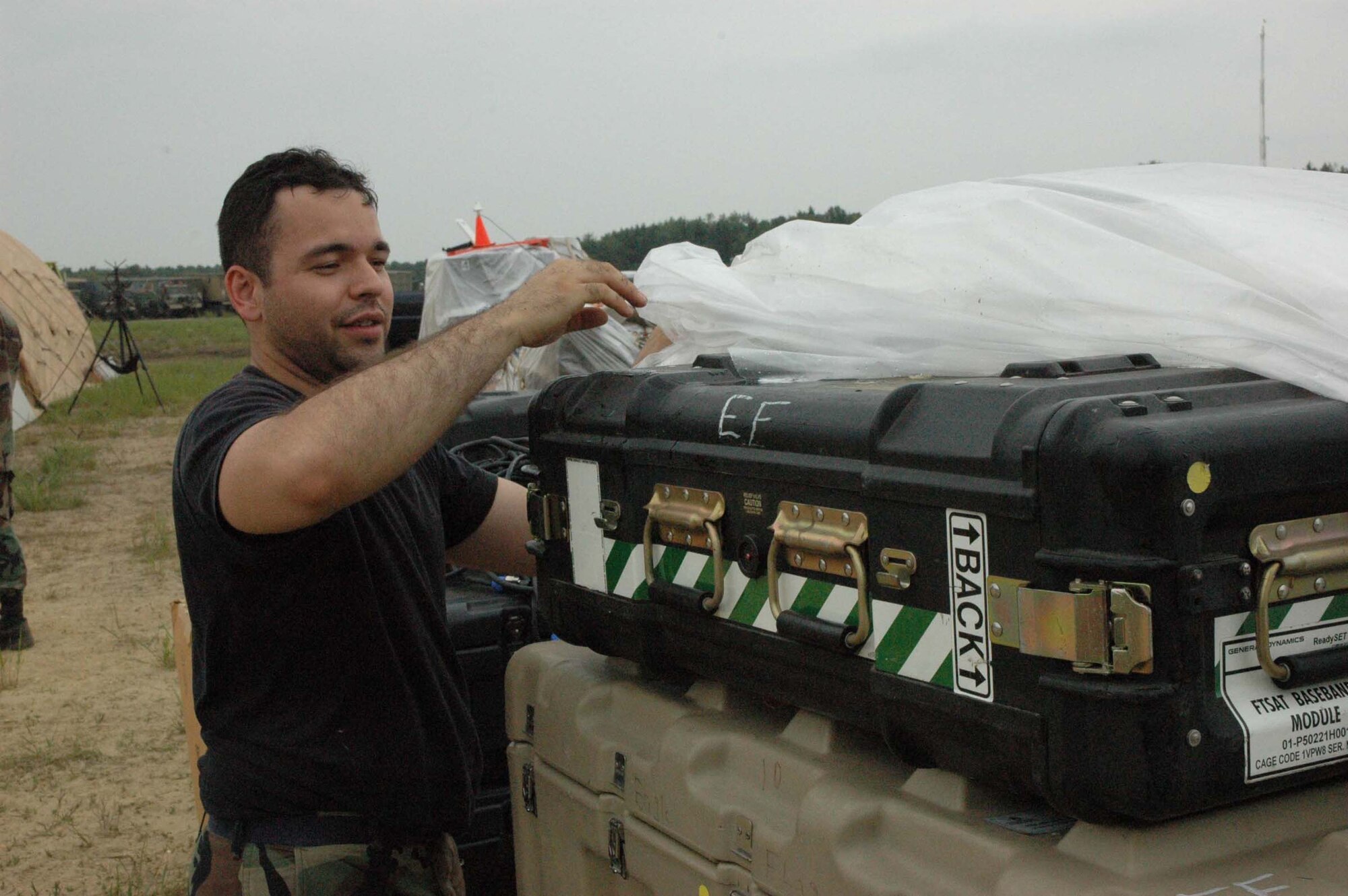 MCGUIRE AIR FORCE BASE, NJ -- Impending strong winds cause Staff Sgt. Joel Rivera, a Reserve satellite communications specailist, to uncover cases to repack equipment during a recent Eagle Flag Exercise held at Lakehurst Naval Air Station, Lakehurst, N.J. Eagle Flag gives participants an opportunity to practice opening an airbase under bare base conditions.  (U.S. Air Force photo/Master Sgt. Donna T. Jeffries)