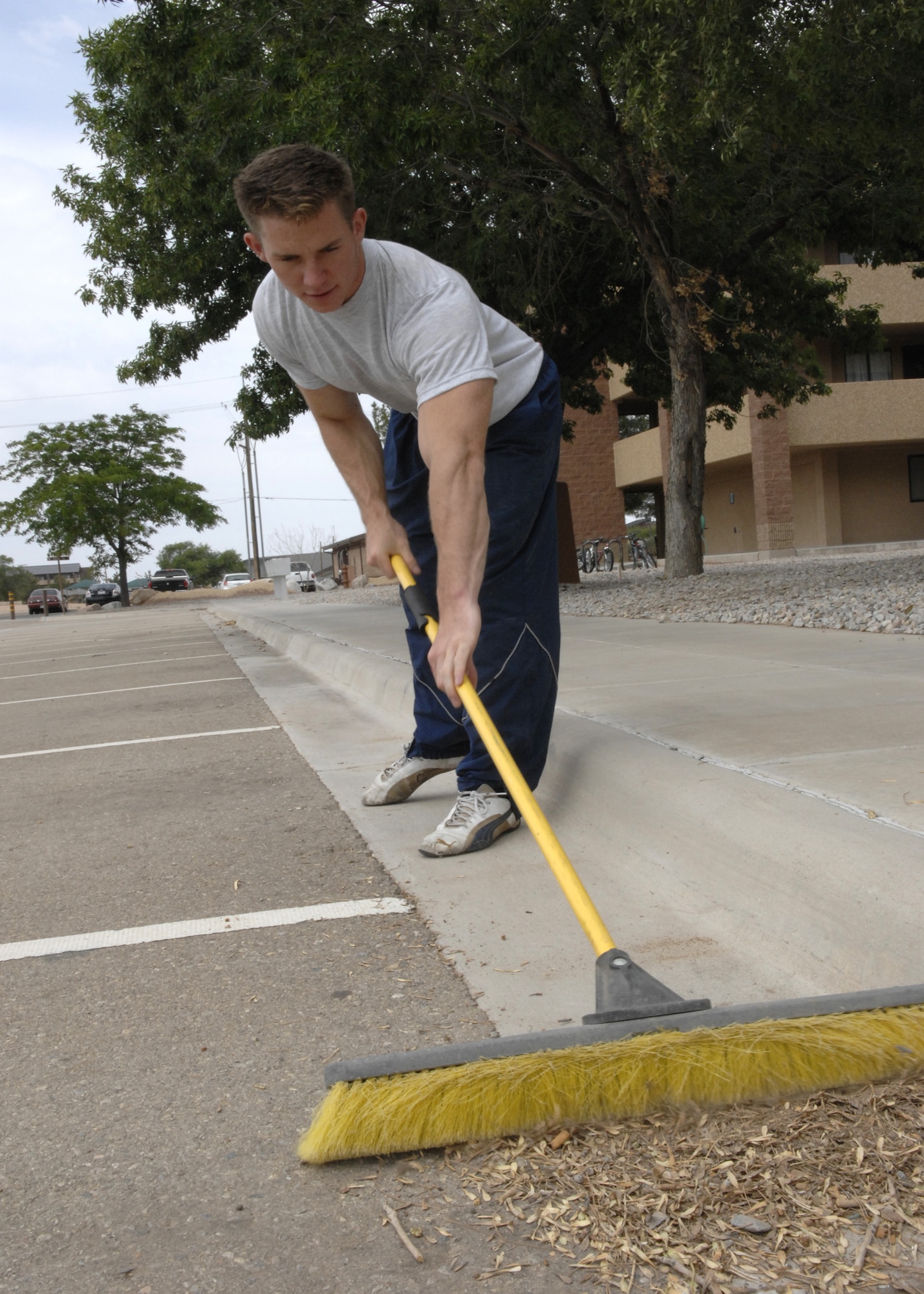 Senior Airman Frank Weiss, 49th Security Forces Squadron, sweeps away rocks while on bay orderly, June 25 outside of building 341 on Holloman Air Force Base, N.M. Bay orderly is a week long detail performed by Airmen living in the dorms. (U.S. Air Force photo/Airman 1st Class Rachel A. Kocin)