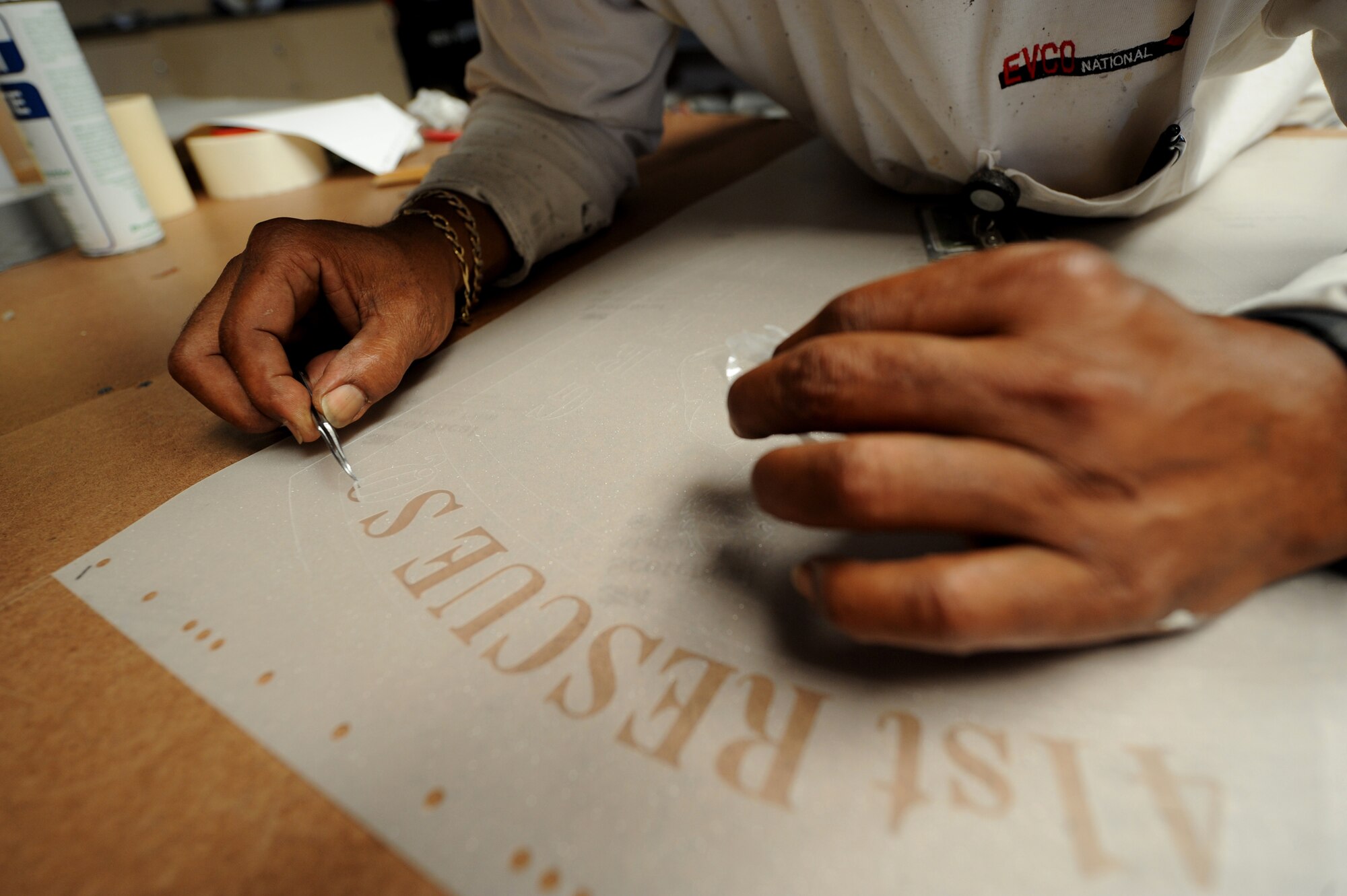 MOODY AIR FORCE BASE, Ga. -- Harvis Fluker, 23rd Civil Engineer Squadron paint shop supervisor, makes a frosted glass decal of the 41st Rescue Squadron patch here June 3. After a computer-driven cutter slices the sticker material, each individual detail must be removed by hand. (U.S. Air Force photo by Senior Airman Gina Chiaverotti)