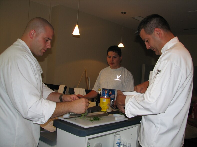 Tech. Sgt. Jason Simas and Staff Sgt. Michael Leo.  Prepare a lavish fest for Airmen at the Center for the Intrepid.  Airman 1st Class Kevin Krogh assists in the preperation.
The Sergeants are enlisted aides to the AETC commander and vice commander.  They volunteered their culinary talents to support sevice members in treatment at the center.  (U.S. Air Force photo/Beverly Simas)