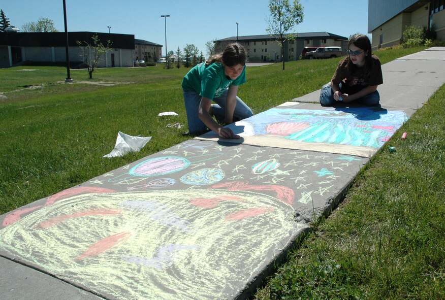 Mackenzie Geigle and Sarah Clark, both 11, place finishing touches on their aquatic chalk artwork during the Youth Program Center's annual Chalk-it-Up! competition Wednesday. (U.S. Air Force photo/ Airman 1st Class Dillon White)