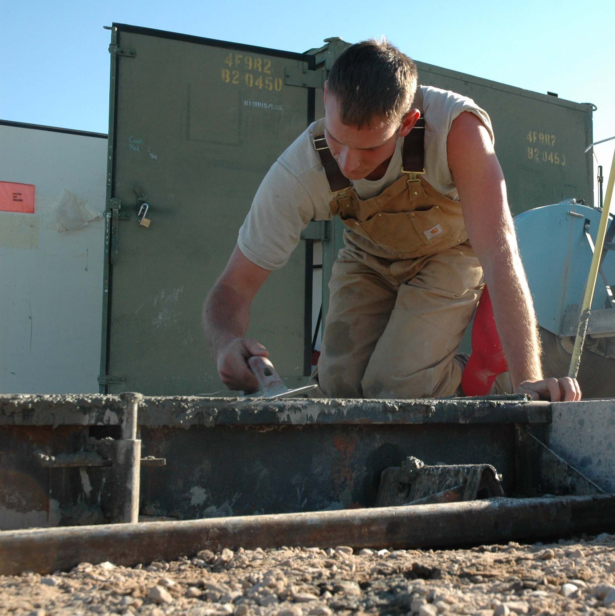Senior Airman Matt Sywassink, 819th RED HORSE Squadron, smoothes concrete near the base heat plant Friday. The Airmen are building a concrete pad which will expand the heat plant's coal capacity to 12,000 tons, enabling the plant to save money by stockpiling coal when prices are lower. (U.S. Air Force photo/ Airman 1st Class Dillon White)