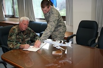 HANSCOM AFB, Mass. - Outgoing 551st Electronic Systems Group Commander Col. Doug Railey completes some final paperwork with the assistance of 1st Lt. Donovan Pavlik, the group's executive officer. (Air Force photo by Liam Murnane)