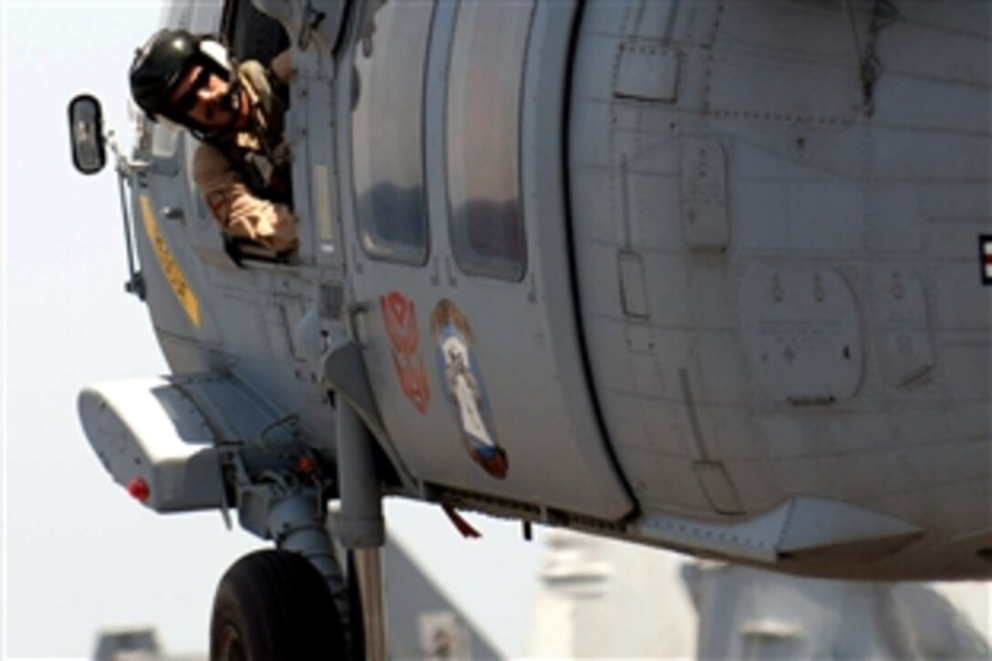 A U.S. sailor watches the tail of an MH-60S Seahawk as it takes off from the flight deck of the air-craft carrier USS Abraham Lincoln during a vertical replenishment with the Military Sealift Command fast combat support ship USNS Rainer in the Persian Gulf, June 23, 2008. 