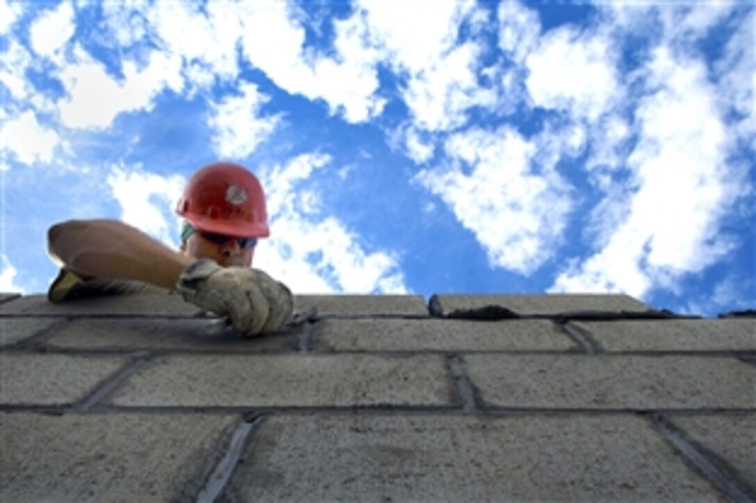 U.S. Air Force Staff Sgt. Joshua Hallmark clears excess mortar from cinder blocks for building a new medical clinic in Yanama, during New Horizons - Peru, June 23, 2008. New Horizons is a U.S. and Peruvian humanitarian mission to provide relief to underprivileged Peruvians. Hallmark, a civil engineer, is assigned to the 820th RED HORSE Squadron, Nellis Air Force Base, Nev. 